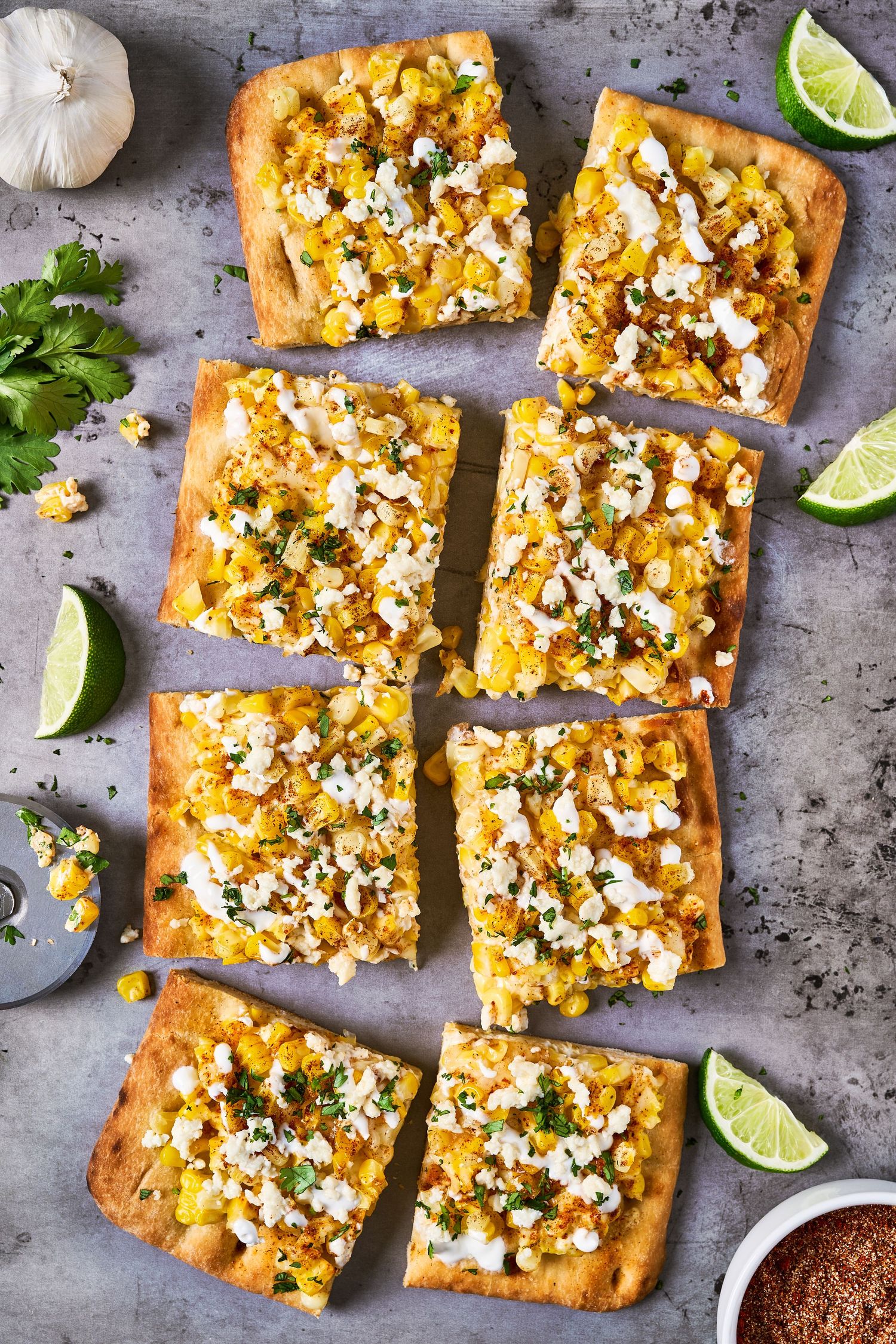 Mexican street corn flatbread topped with cotija cheese, cilantro and spices on a rustic baking sheet.