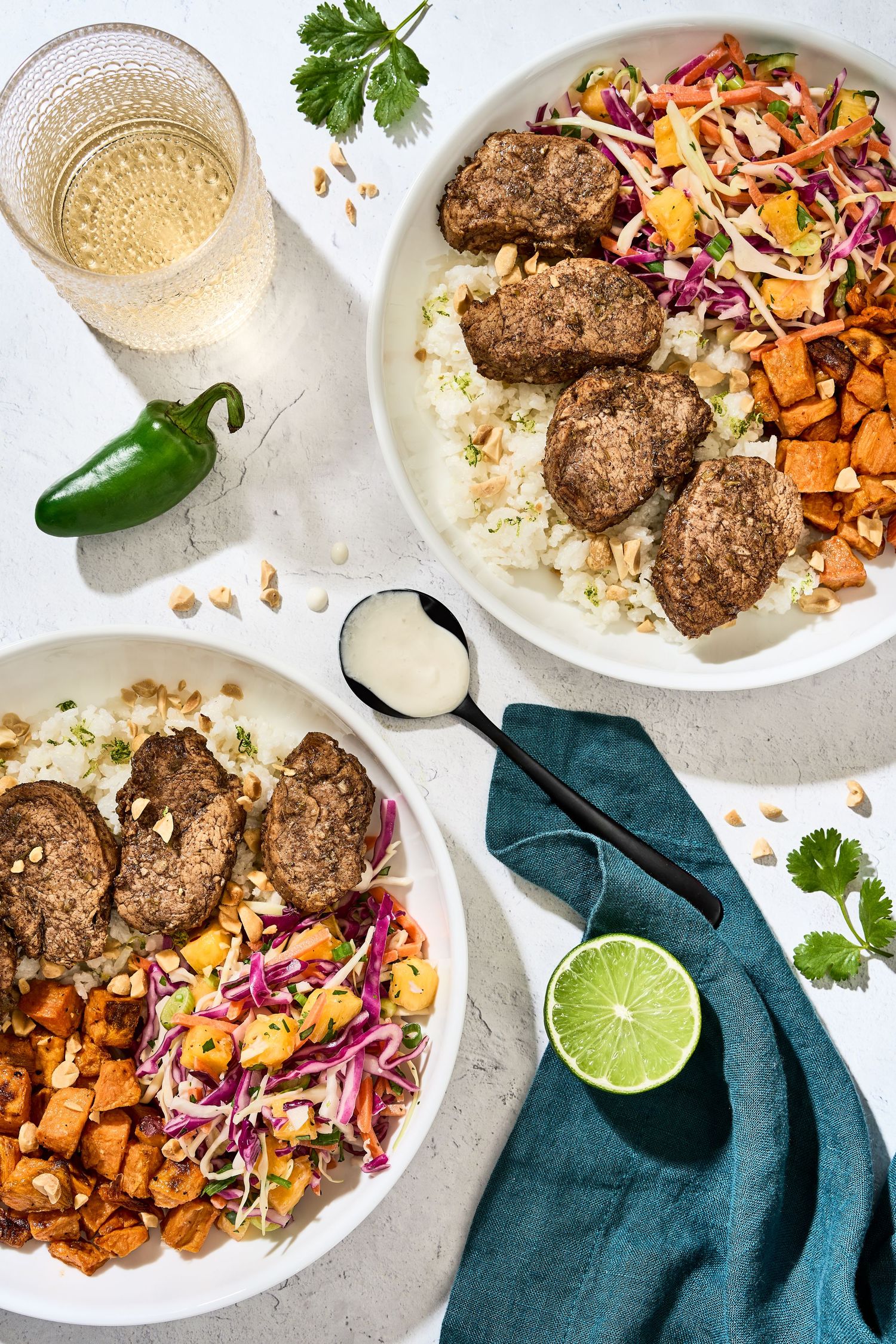 Moroccan-spiced meatballs with roasted sweet potatoes, couscous, and cabbage slaw garnished with herbs and lime.
