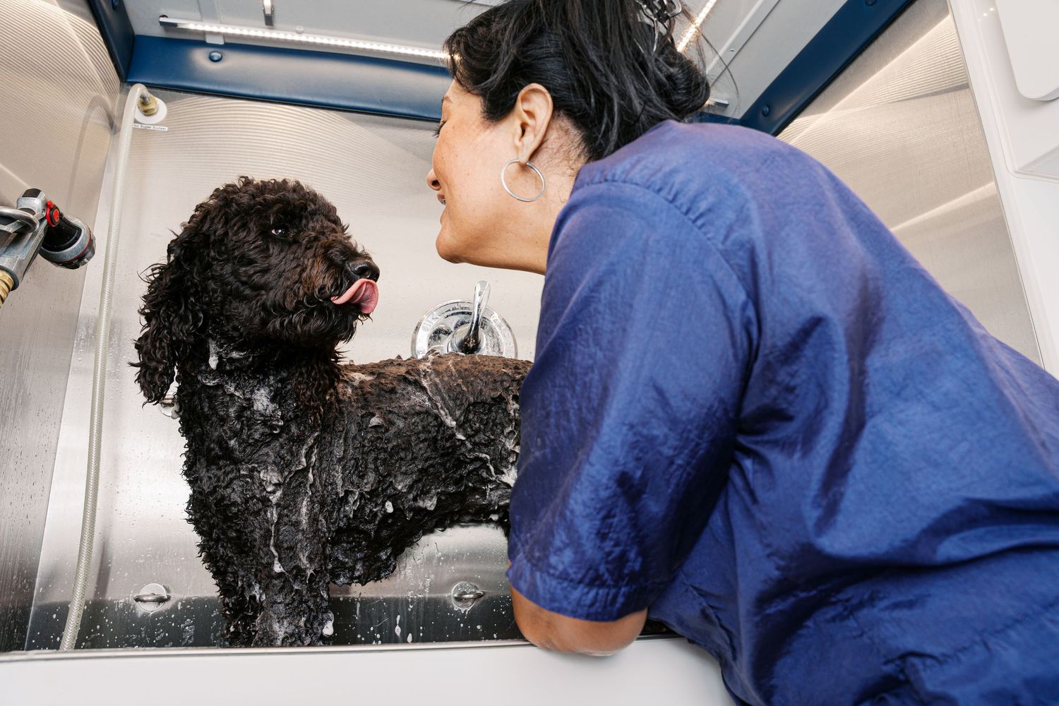 Medical professional in blue scrubs performs dental examination and cleaning procedure in modern office setting.