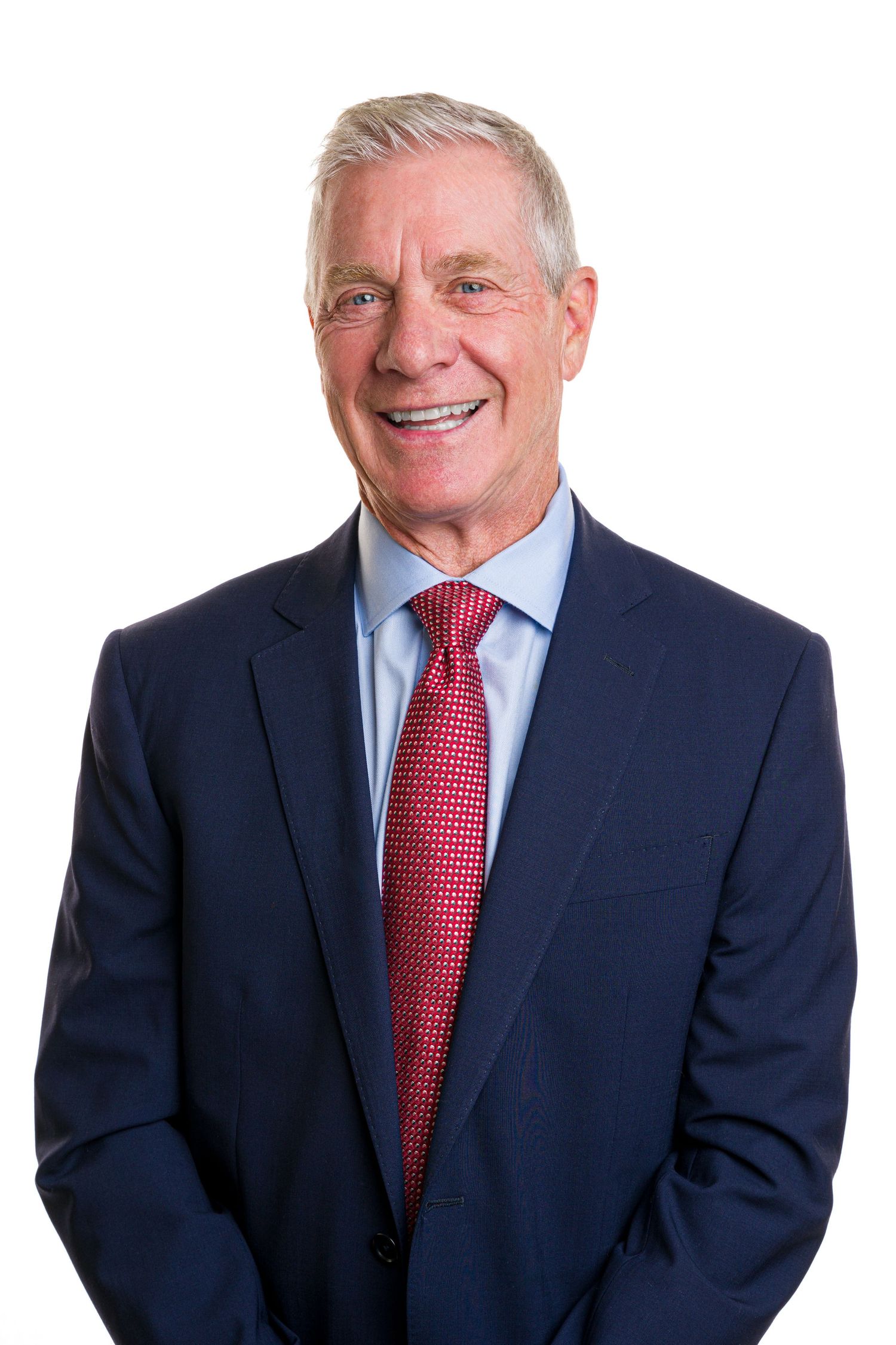 Business professional in navy suit and red tie against white background.