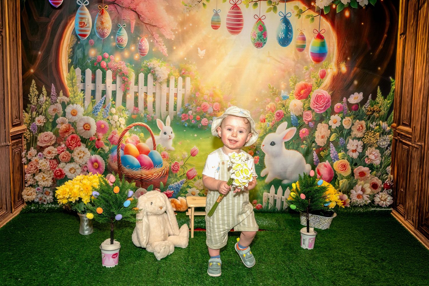 Colorful Easter backdrop with lanterns, picket fence, and spring decorations in a garden setting.