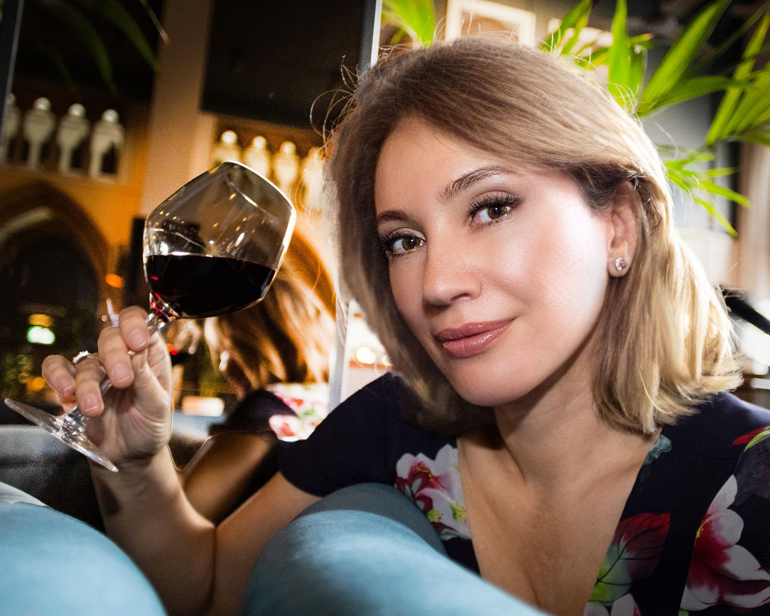 Warm ambient photo of someone holding a glass of red wine in a restaurant setting. Bristol photo in a bar