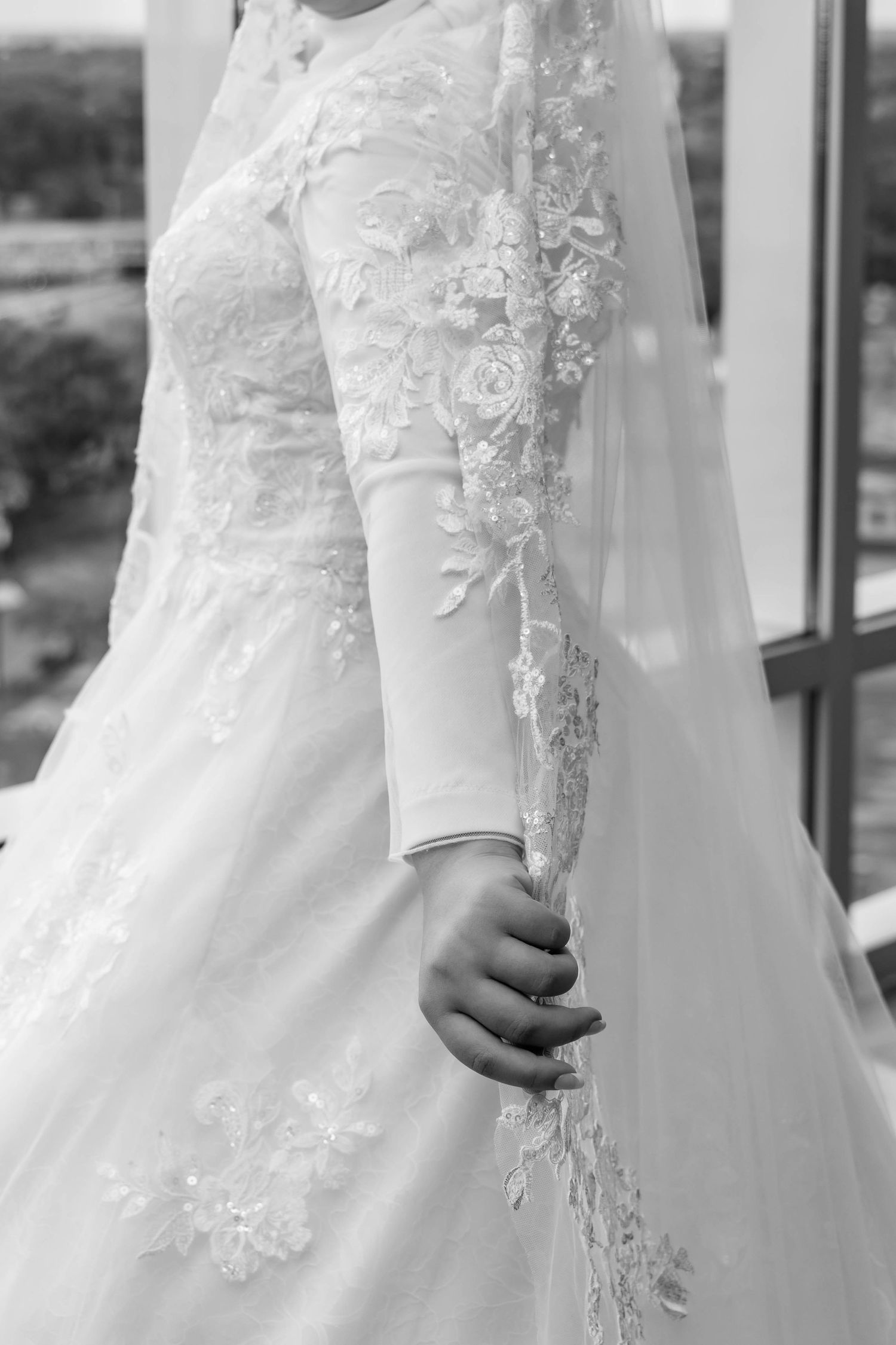 Close-up detail of intricate lace appliques on long-sleeved white wedding gown.