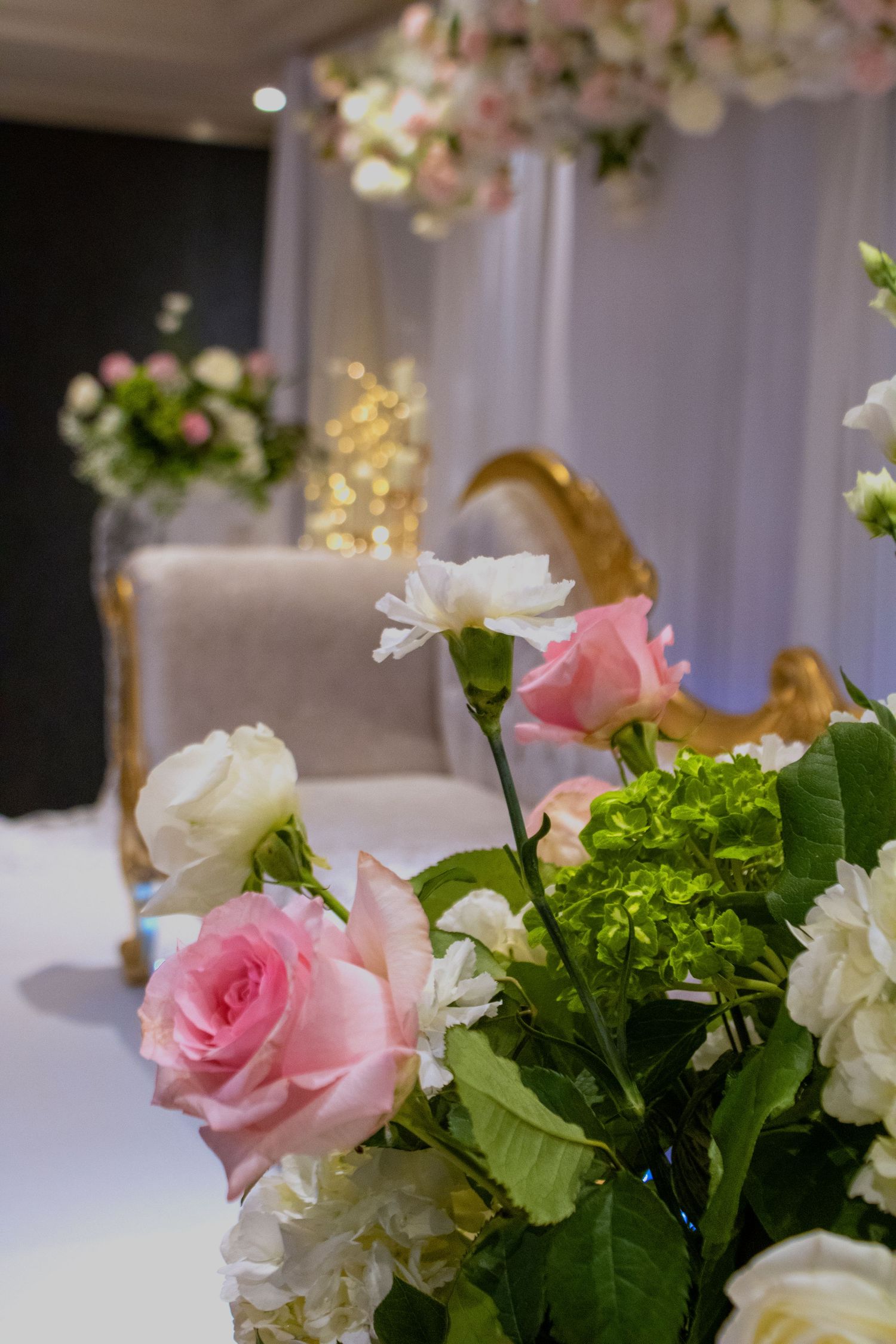 Elegant floral arrangement with pink roses and white flowers at a formal event.