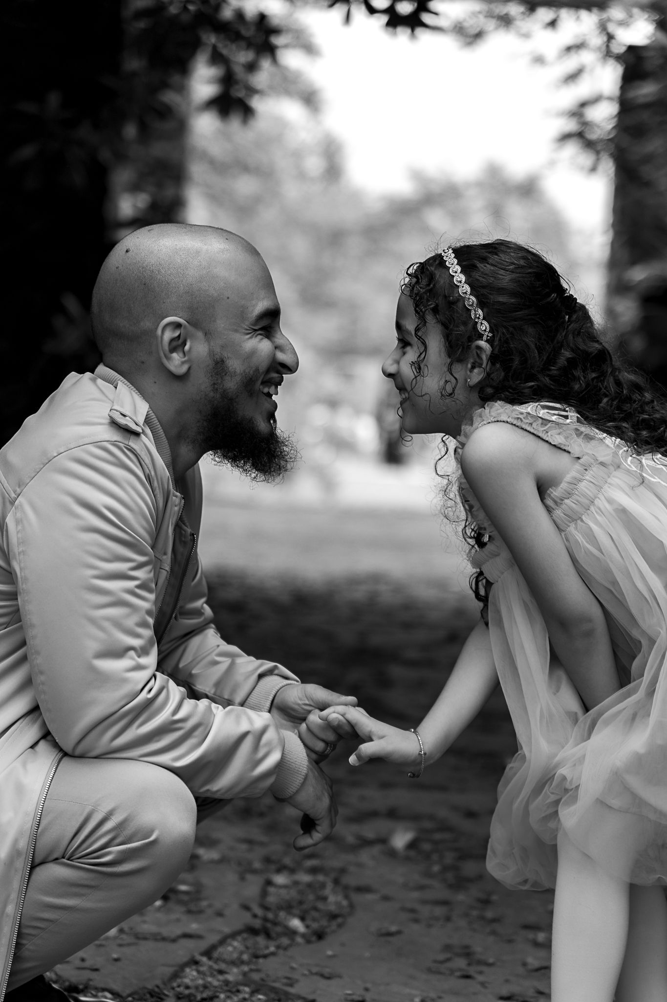 Sweet black and white photo of a father and daughter sharing a tender moment in a garden setting.