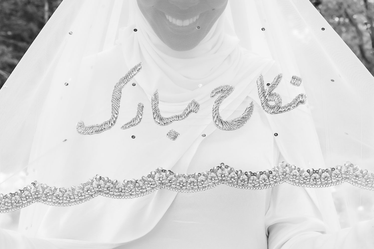 Elegant Arabic calligraphy embroidered in silver glitter on white bridal fabric. | PHL, PA Wedding Photographer | Desi Weddings