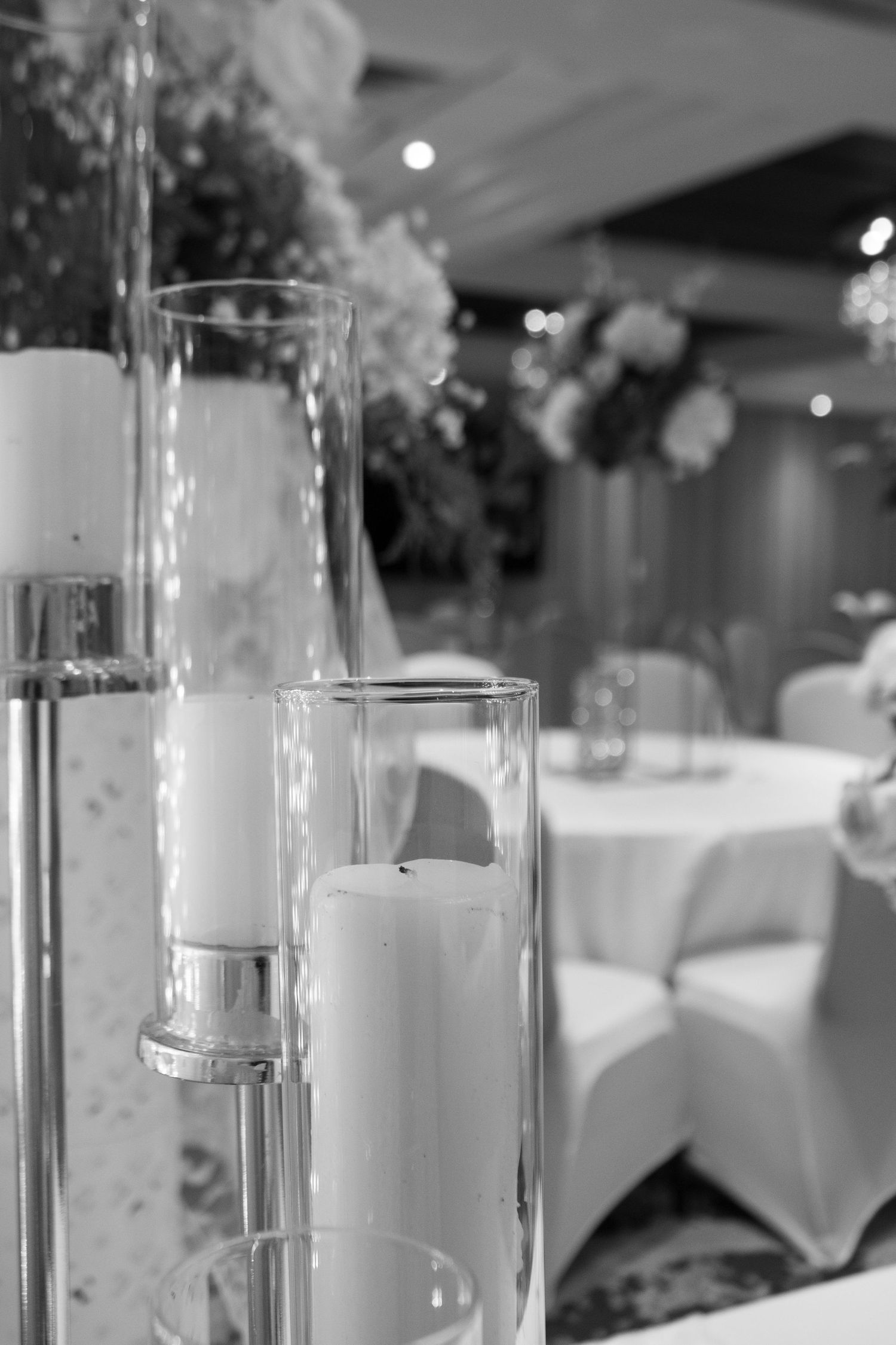 Elegant floating candles in glass cylinders with white floral arrangements at formal reception.
