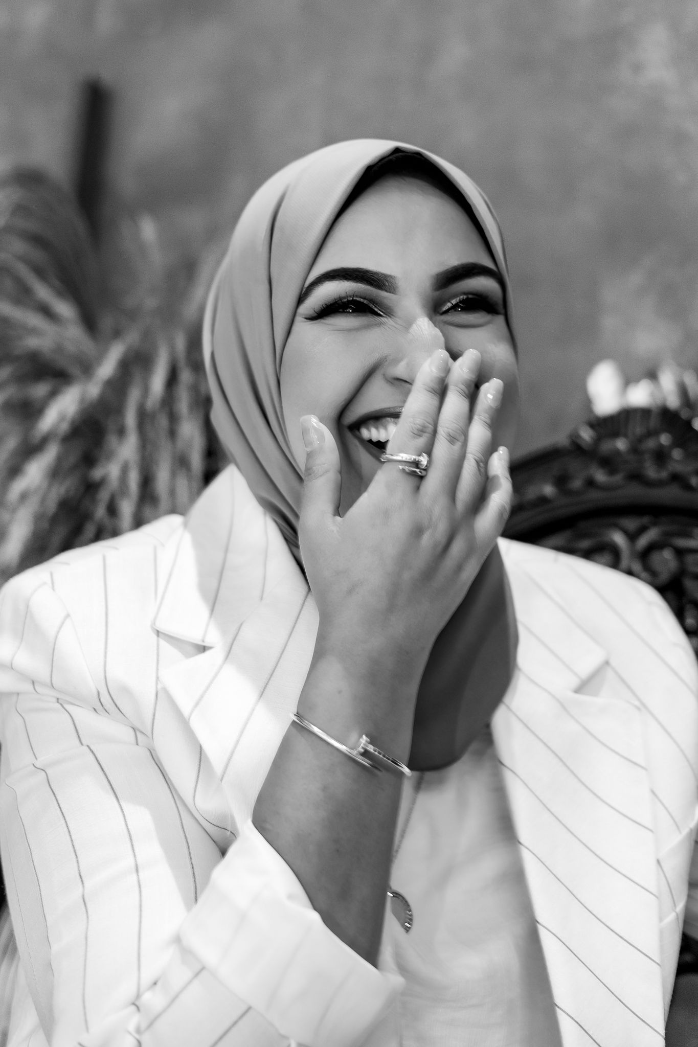 A joyful expression captured in black and white while wearing a white blazer and light hijab.
