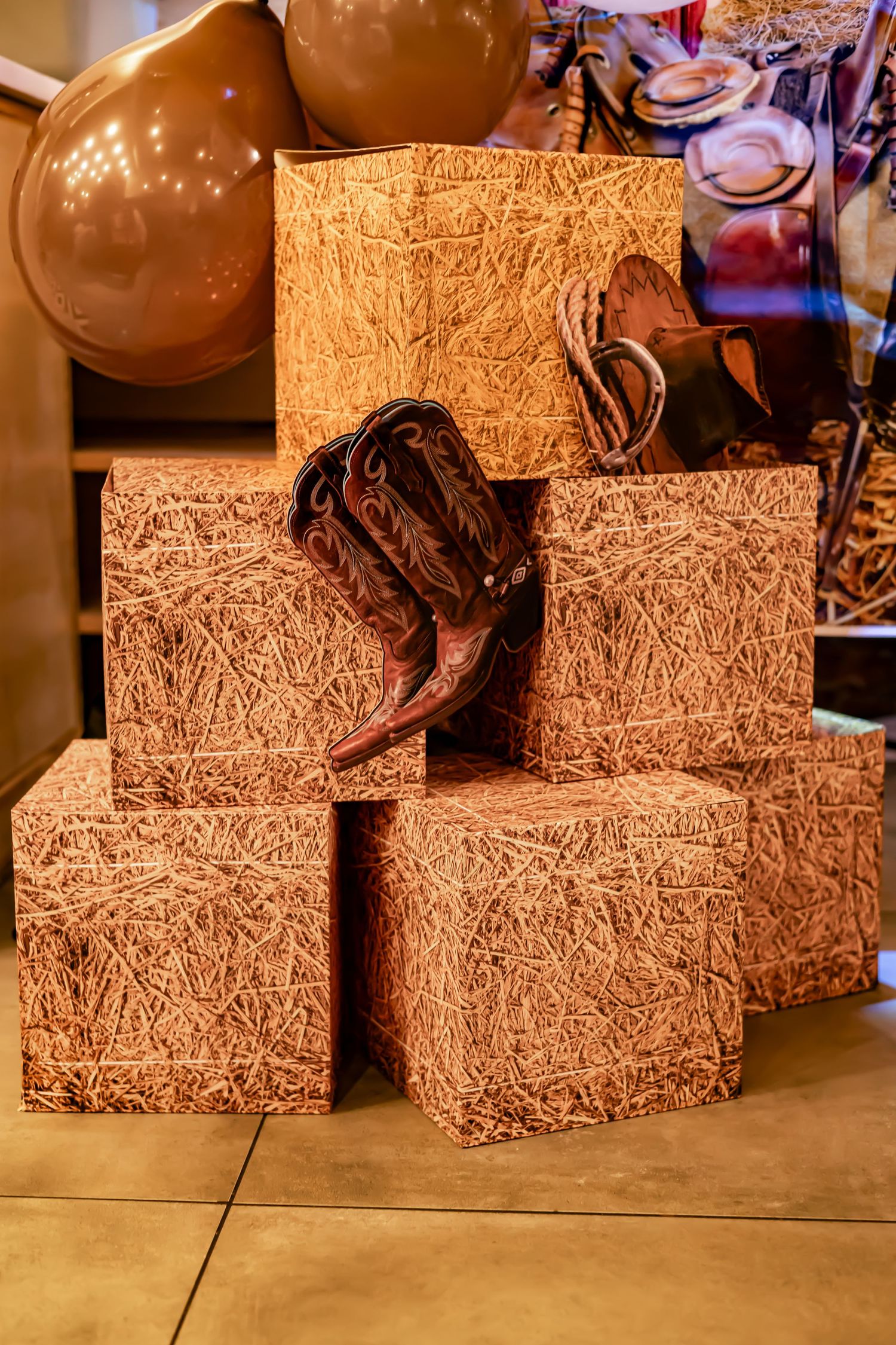 Textured brown gift boxes stacked together with a leather accent piece on a tan surface.
