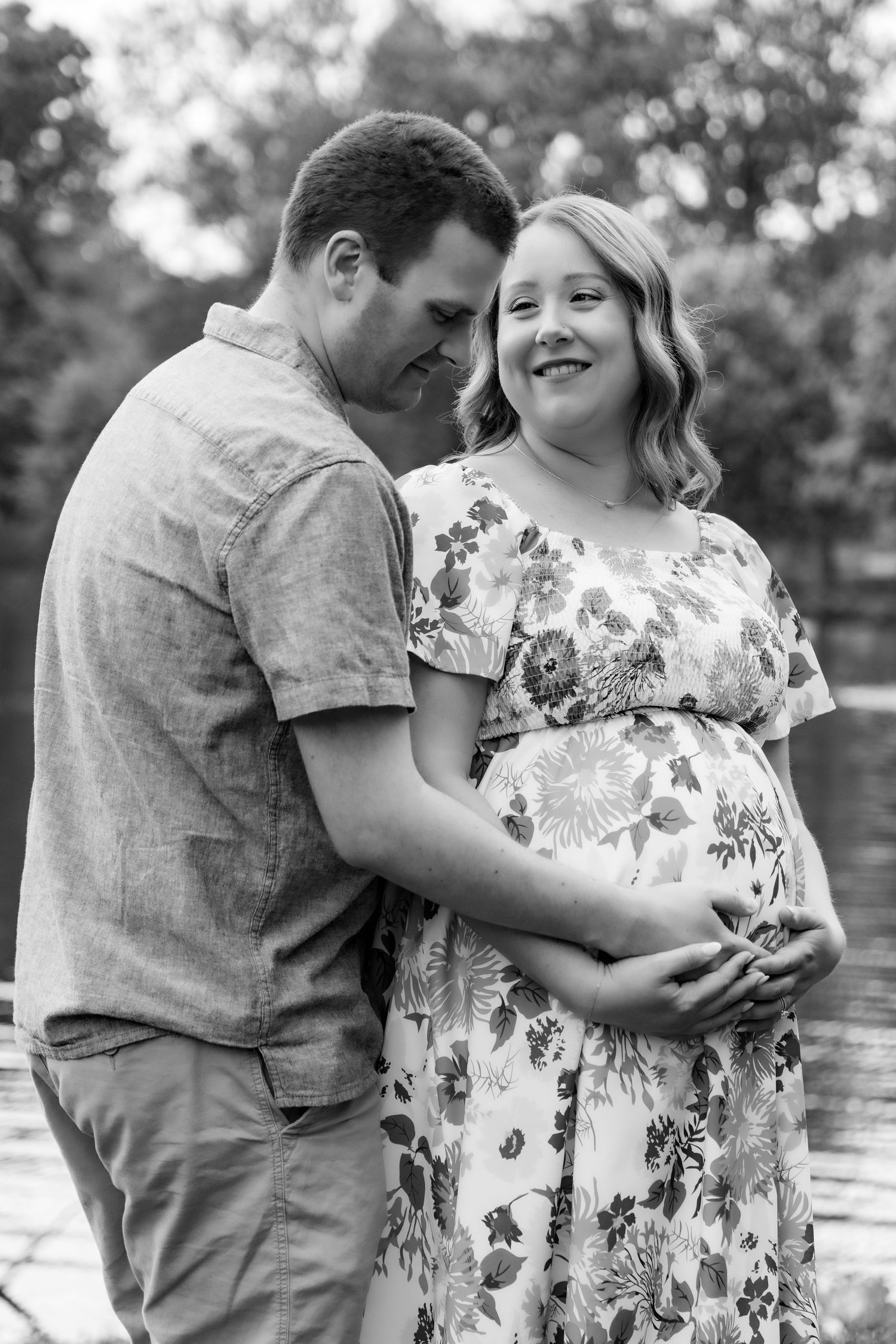 A couple shares an intimate black and white moment together during a maternity photoshoot outdoors.