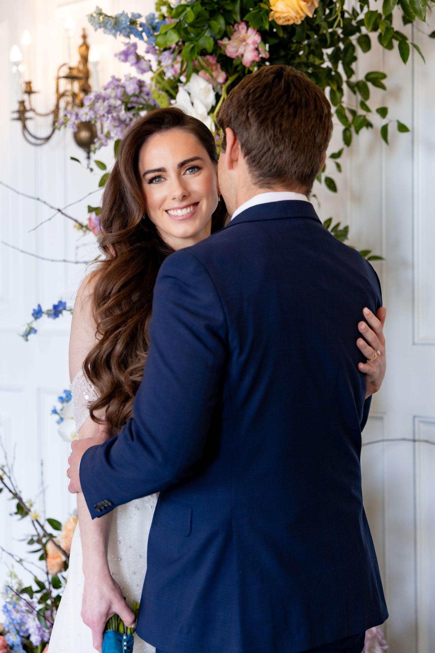 Intimate wedding portrait against floral wall decoration.