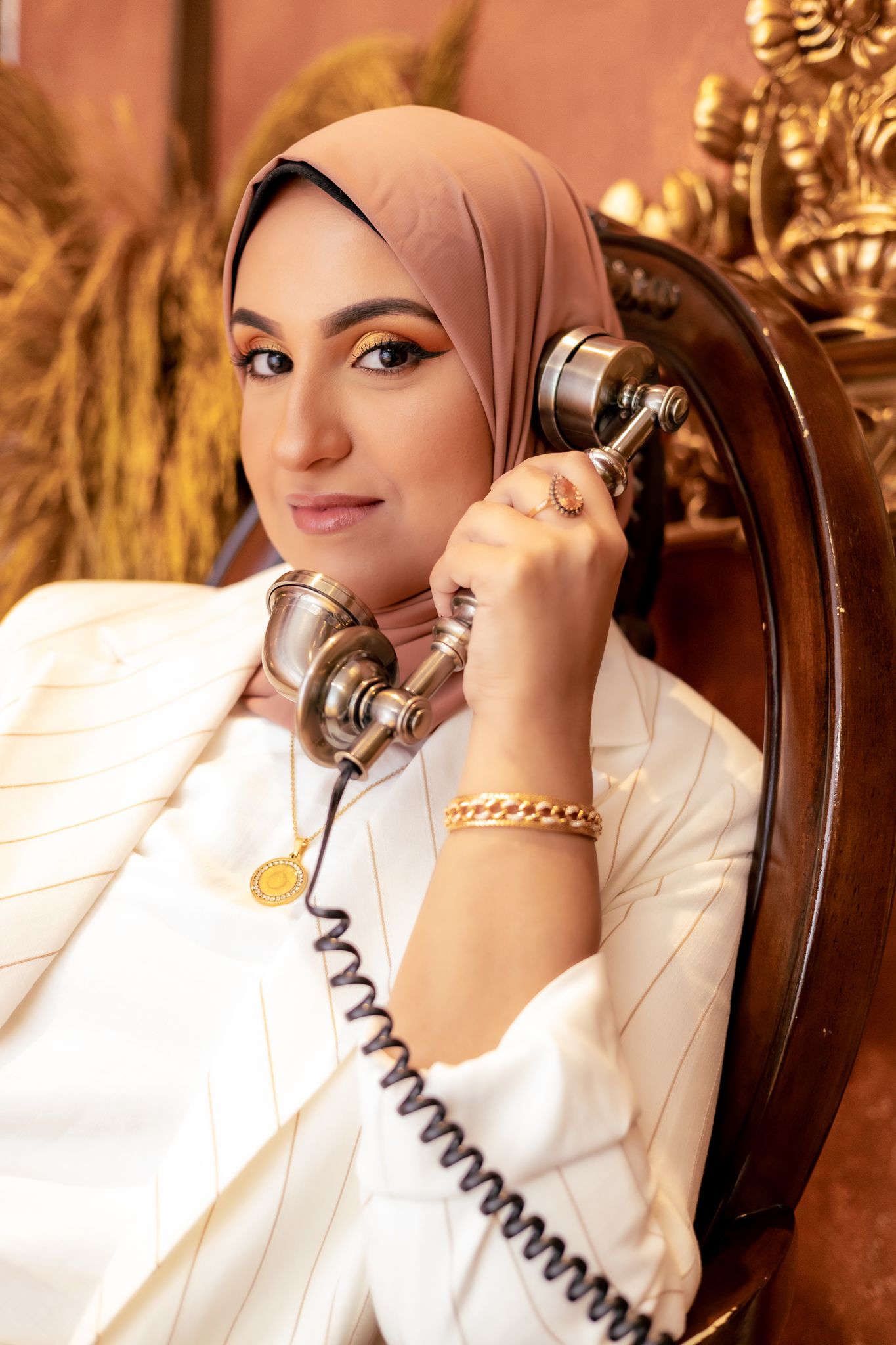 Elegant portrait with vintage telephone and warm lighting in a luxurious setting with classic decor.
