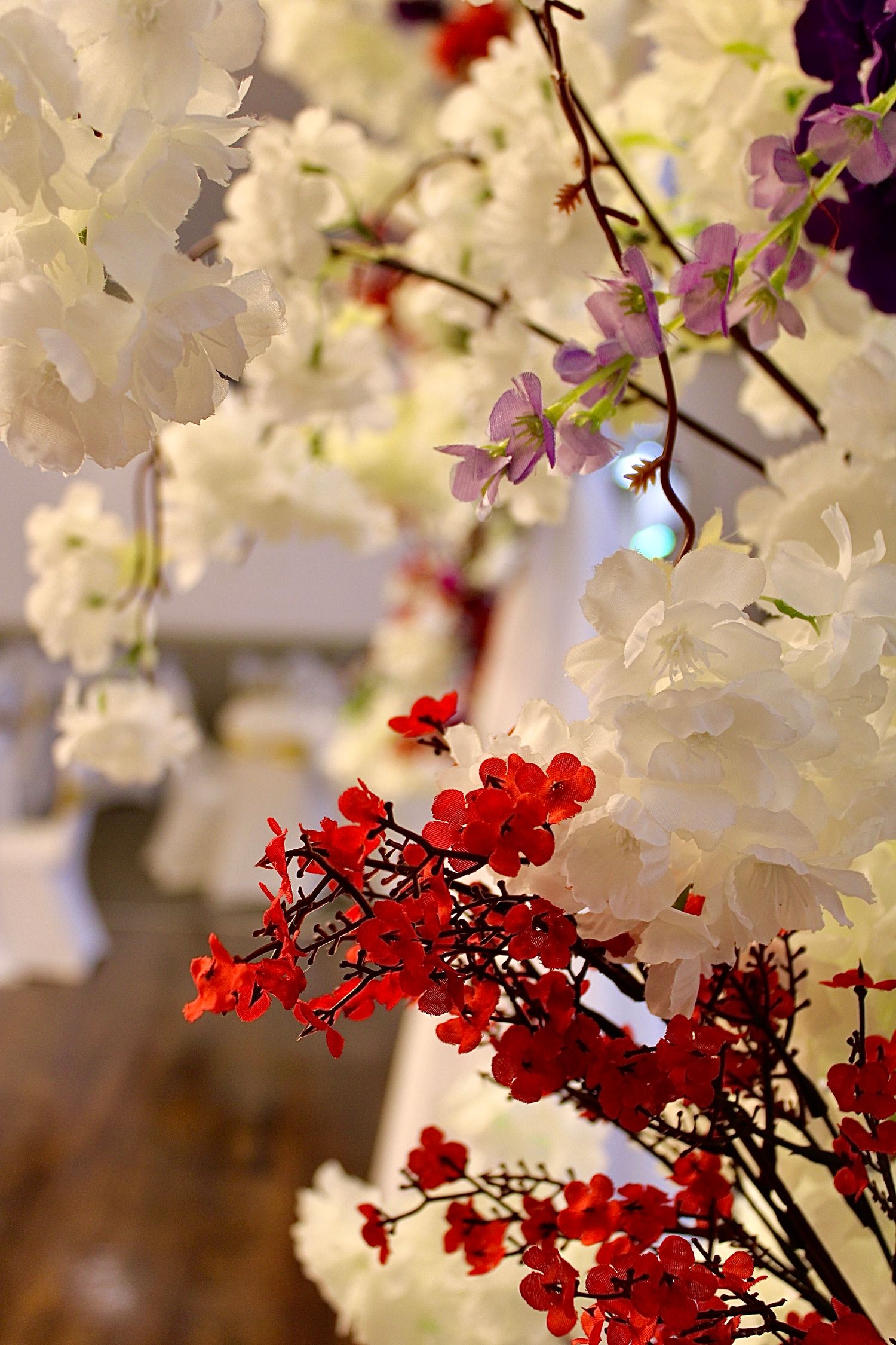 Stunning floral arrangement with white, purple, and red blooms in soft focus.