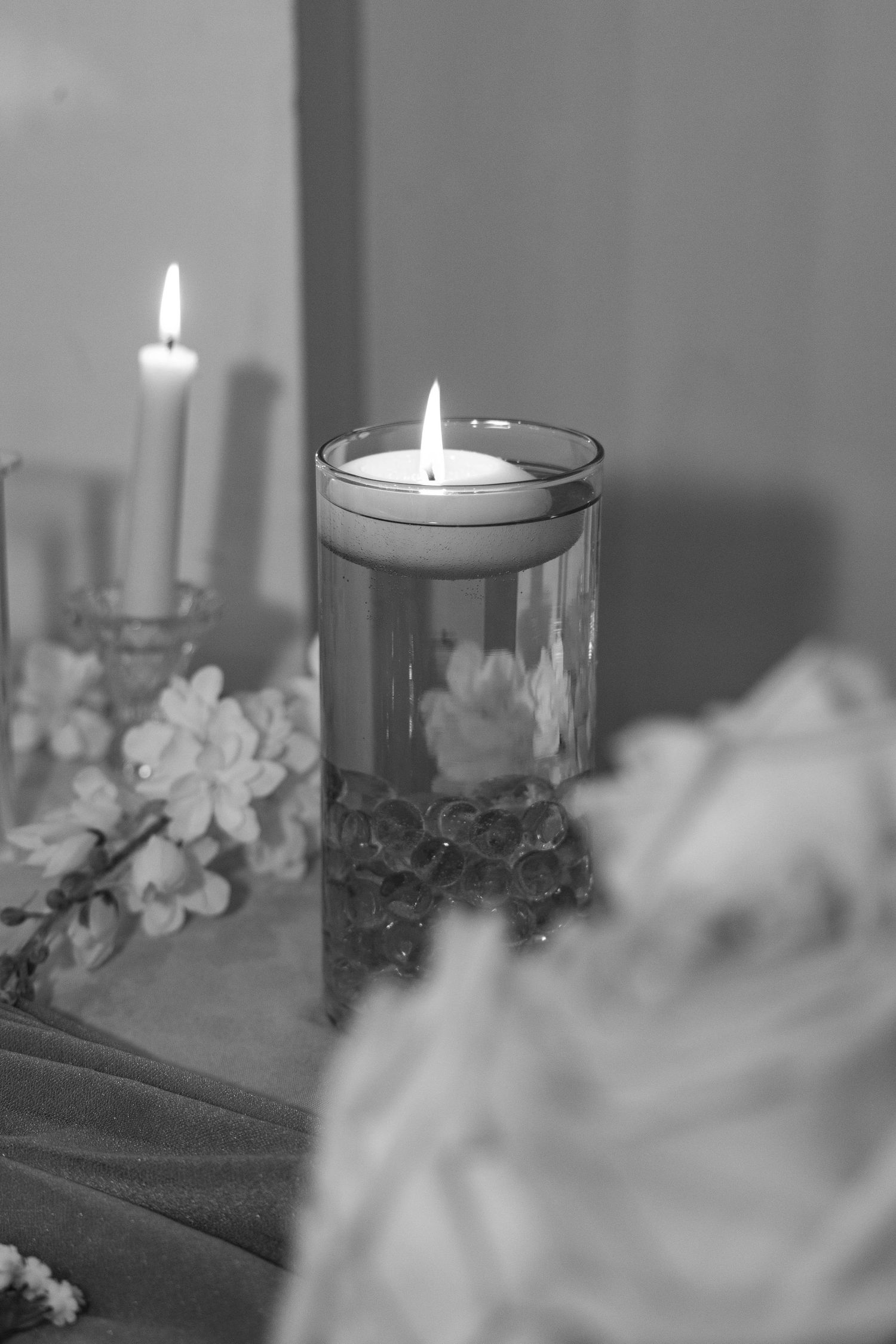 Black and white photo of glowing candle with floral decorations.