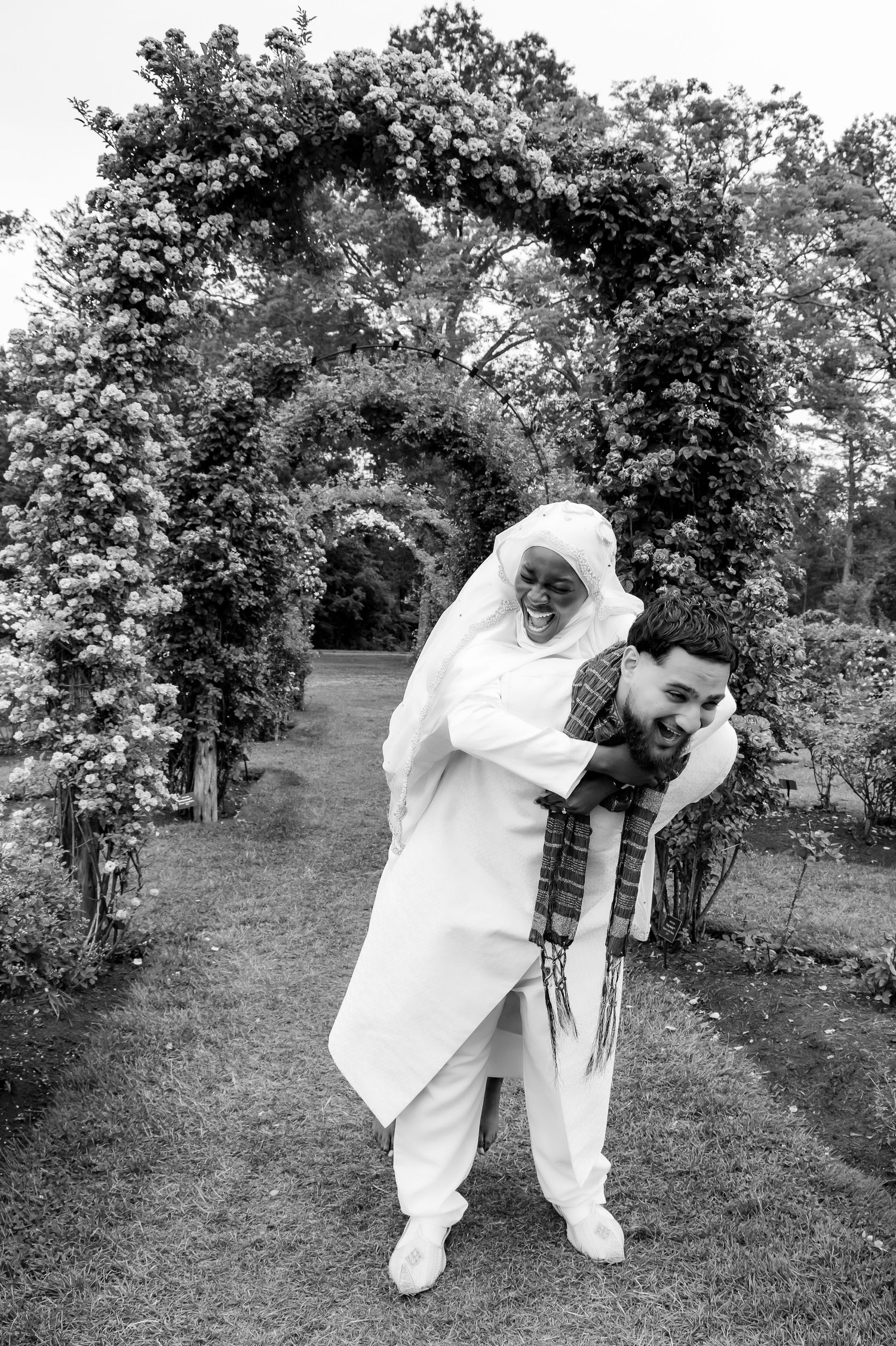 A person in white clothing dramatically bends forward with outstretched arms while posing on a grassy hillside. | PHL, PA Wedding