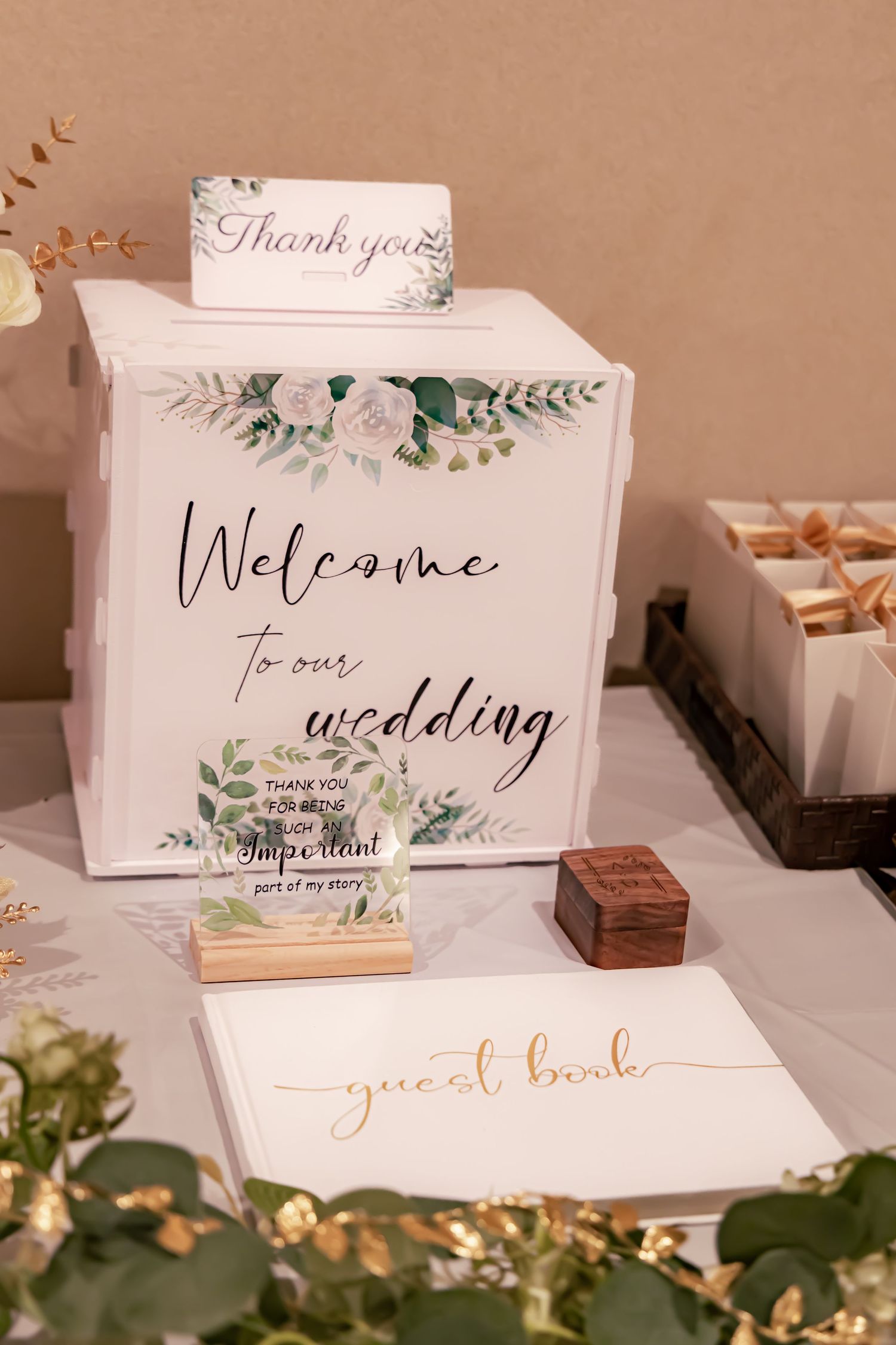 Elegant wedding welcome sign and guest book display with floral design and calligraphy.