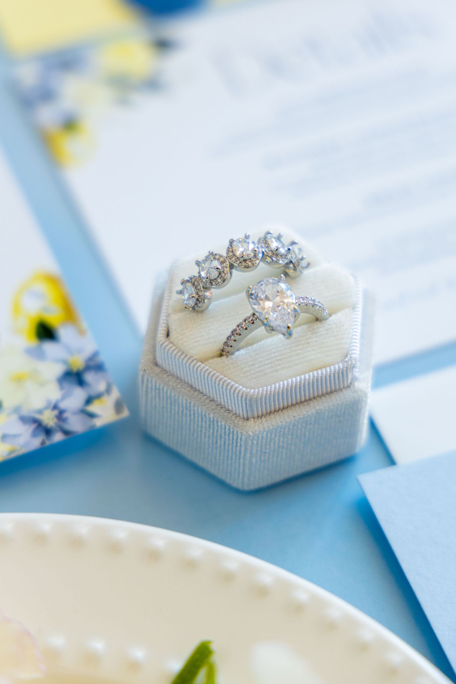 Diamond engagement ring and wedding band set displayed in a pale blue hexagonal box.