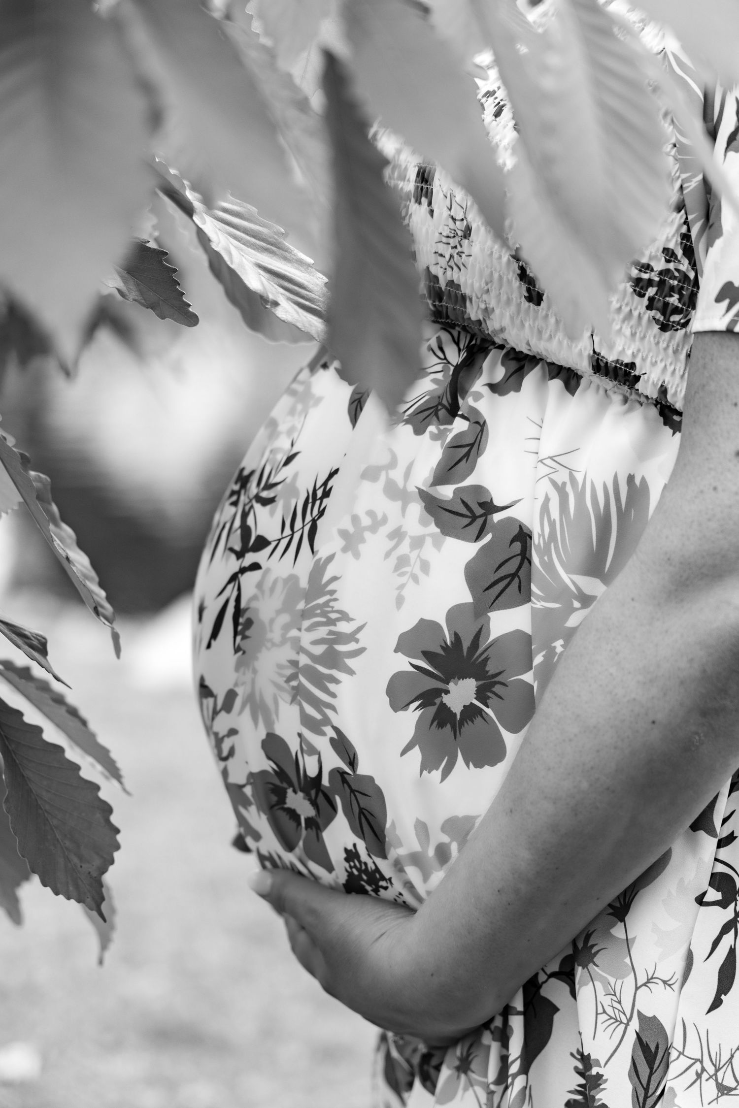 Black and white close-up of a person wearing a delicate floral patterned dress with gentle leaf motifs.