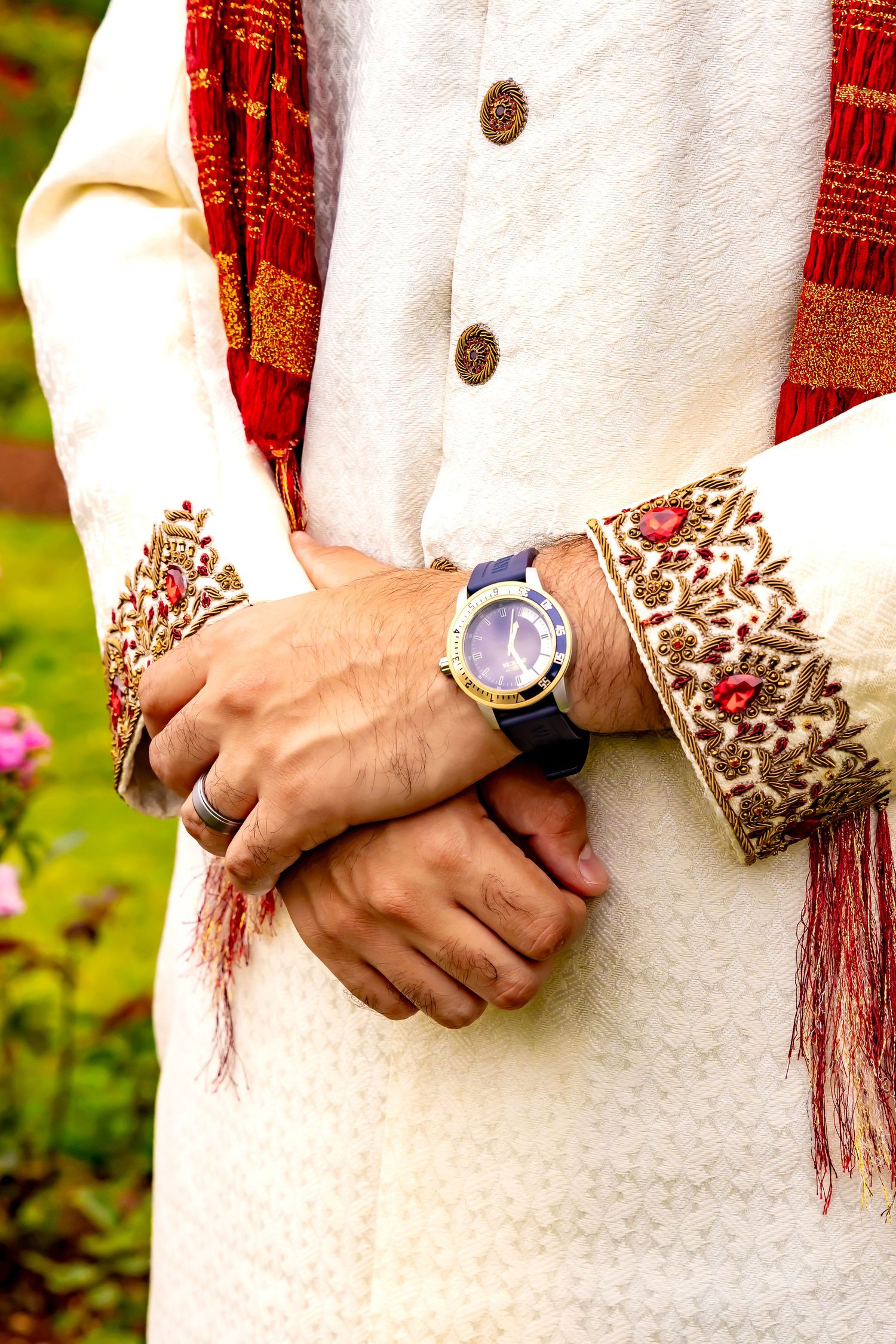 Close-up details of traditional Indian wedding attire showing intricate embroidered cuff details and red dupatta. | PHL, PA Wedding