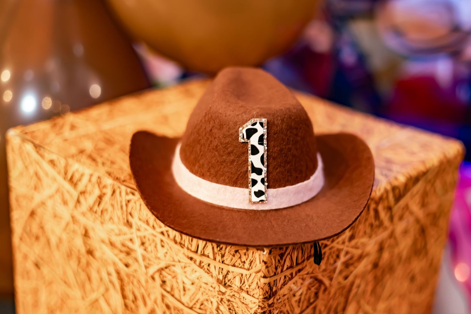 A brown cowboy hat with a decorative white band sits atop a textured wooden box.