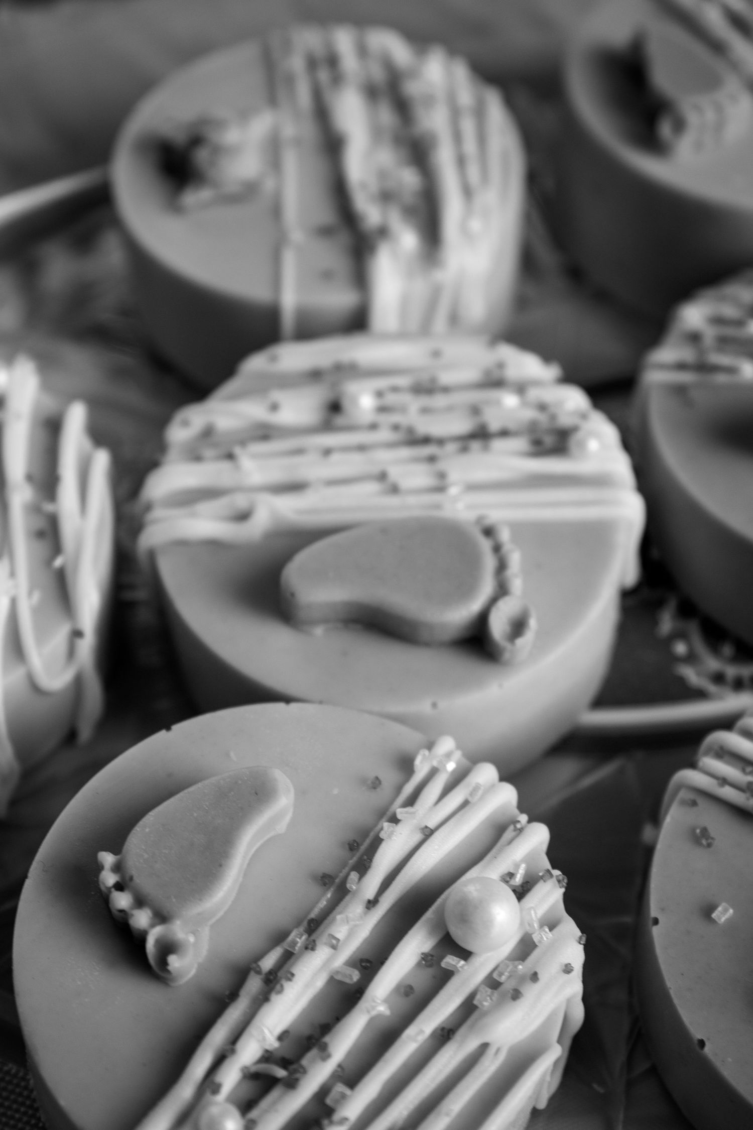 Close-up black and white photo of chocolate covered cookies with drizzled white icing and decorative toppings.