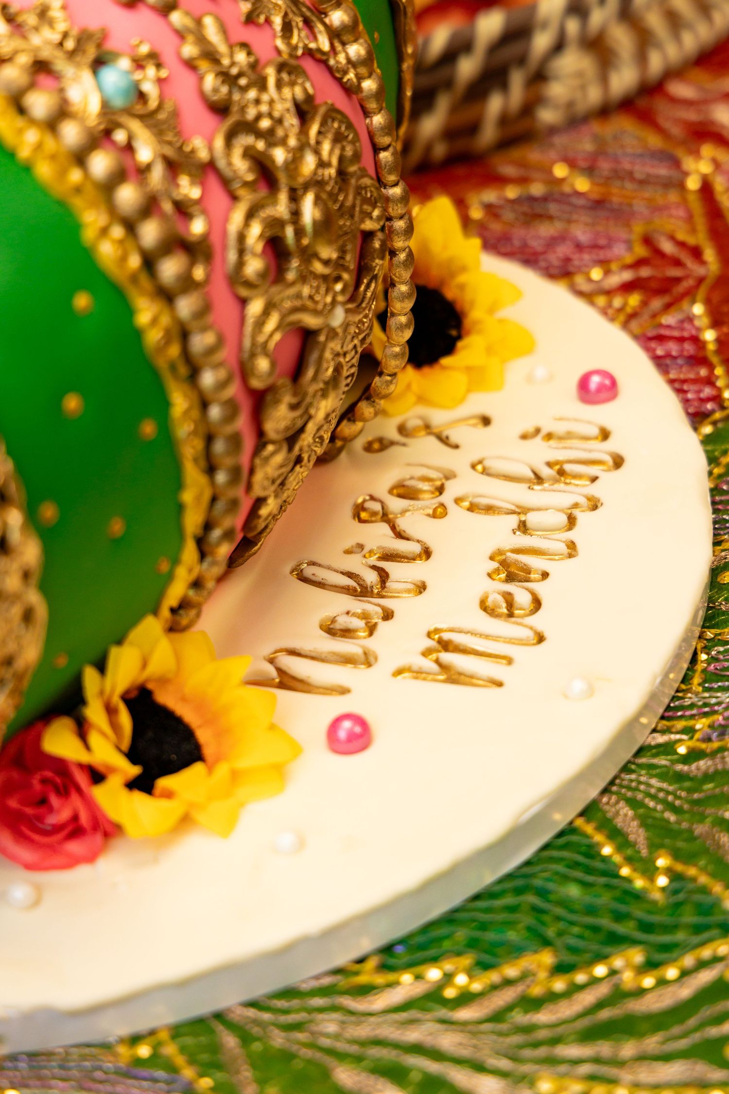 Close-up of a celebration plate with decorative elements featuring gold accents, sunflowers and text on white ceramic.