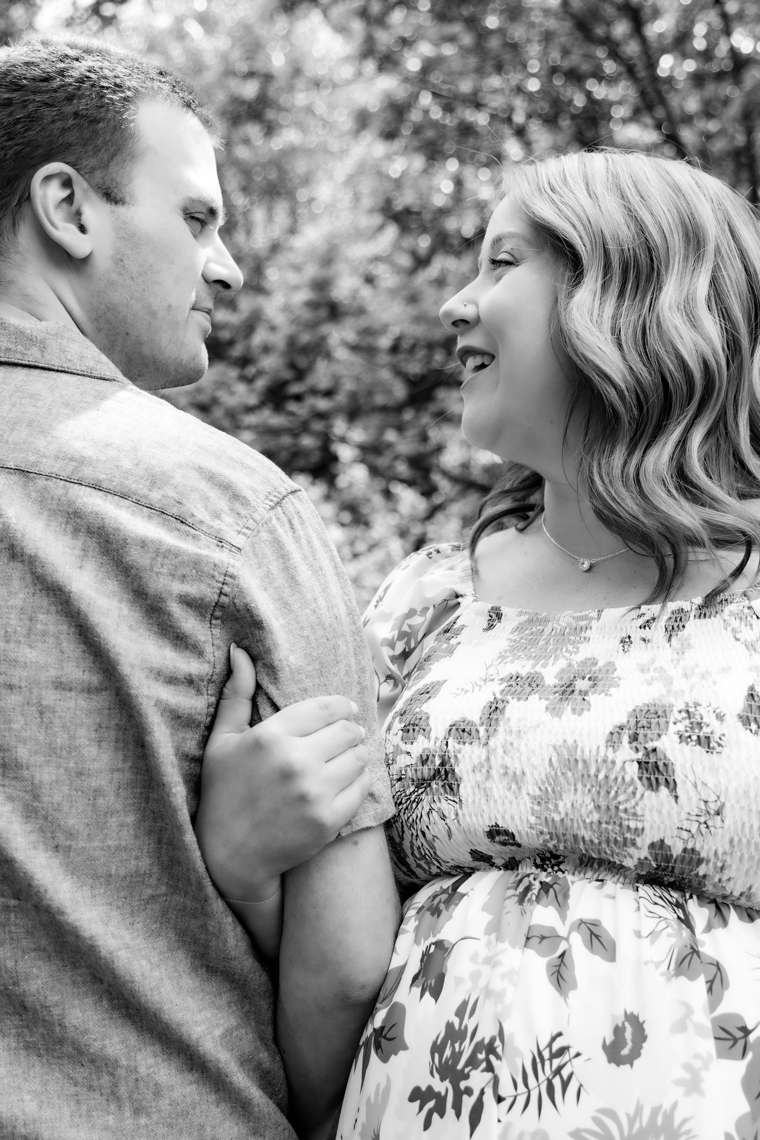 A romantic black and white portrait of two people in an outdoor setting, woman wearing a floral dress.
