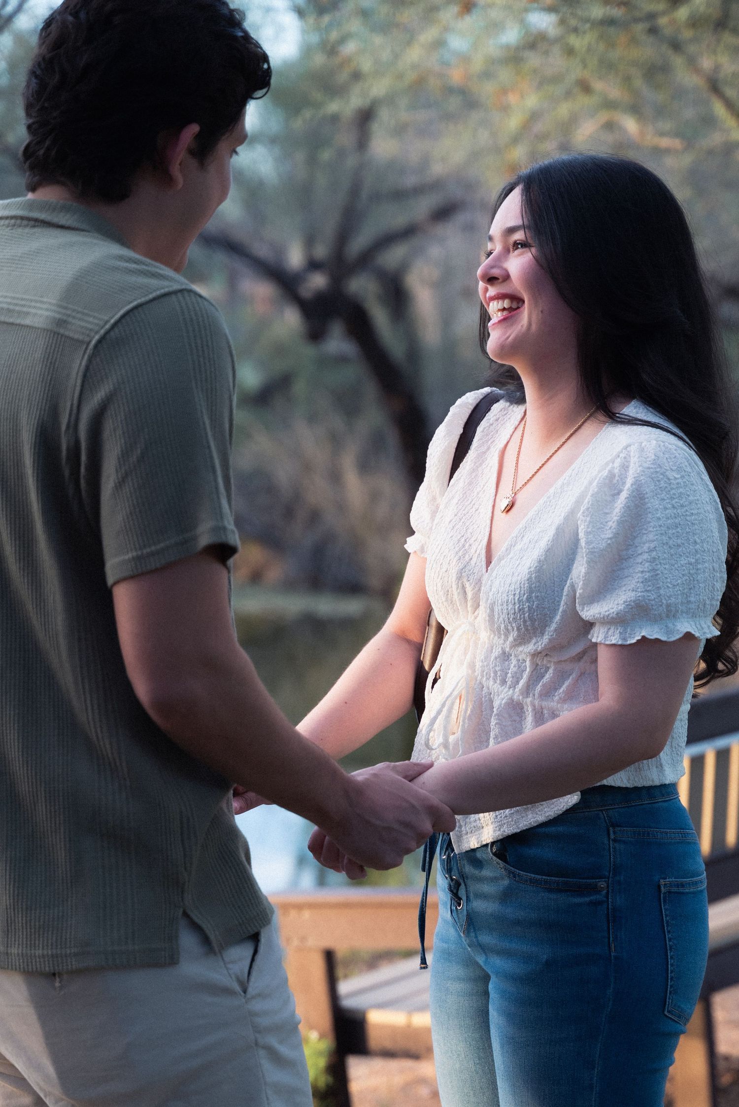 A couple shares a tender moment outdoors in a park setting during sunset.