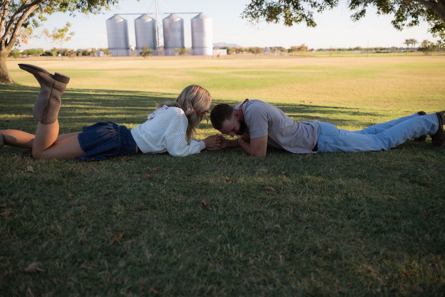 A person lying on their side in green grass during a sunny day at sunset.