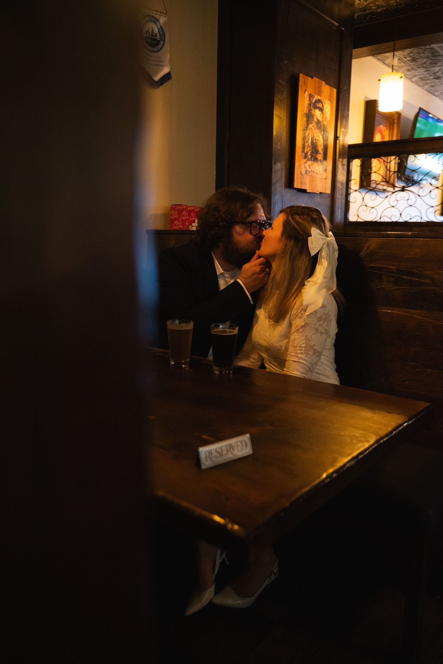 A dimly lit bar or restaurant interior with wooden tables and framed artwork on the walls.