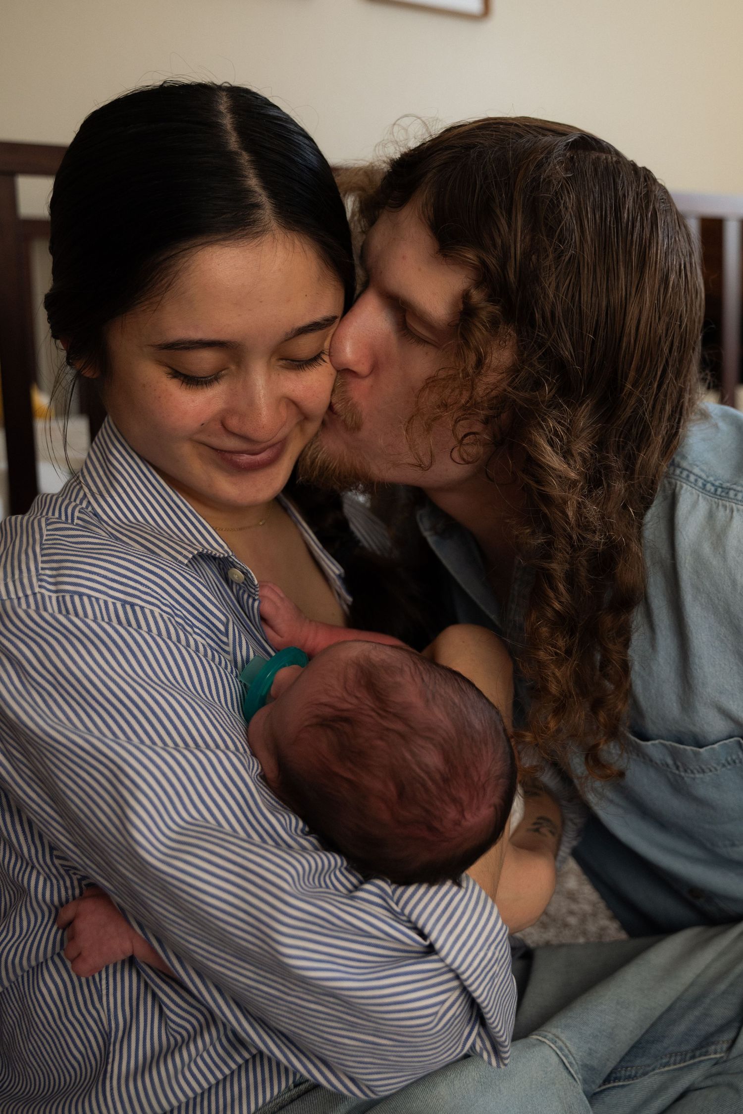 A tender family moment as parents share loving kisses with their newborn baby in a series of intimate photographs.