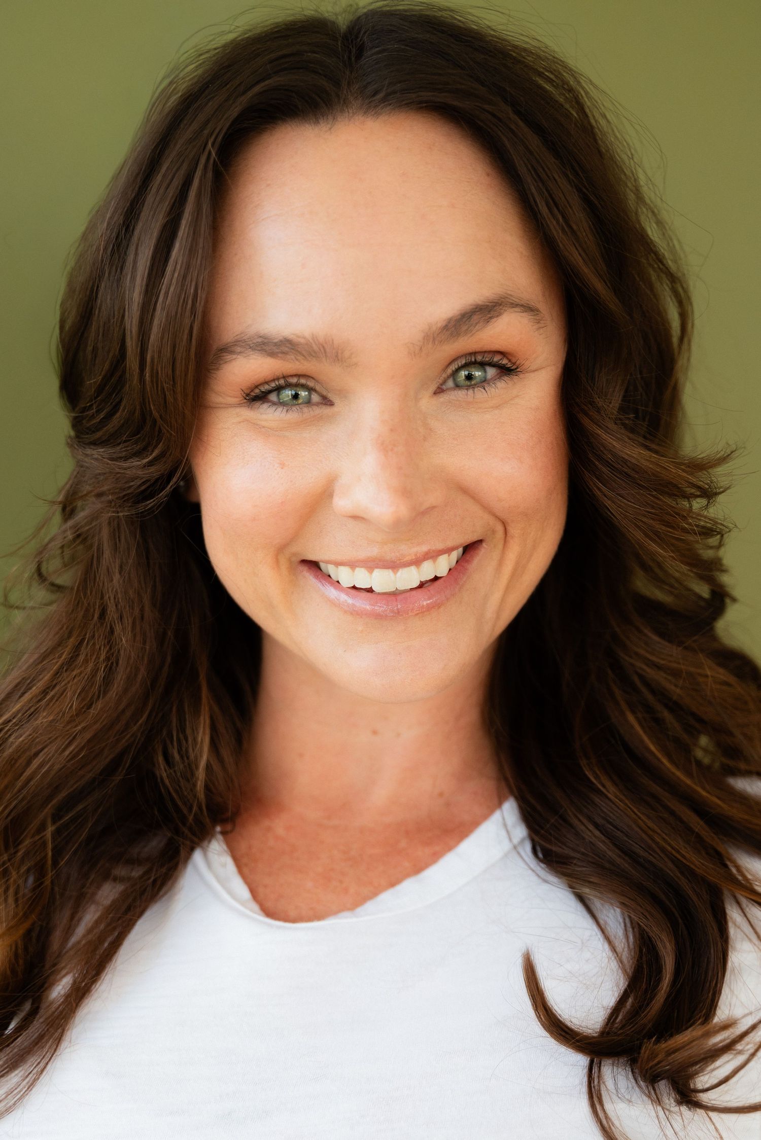 A series of headshots showing a person with dark wavy hair and bright blue eyes wearing a white top against a light background.