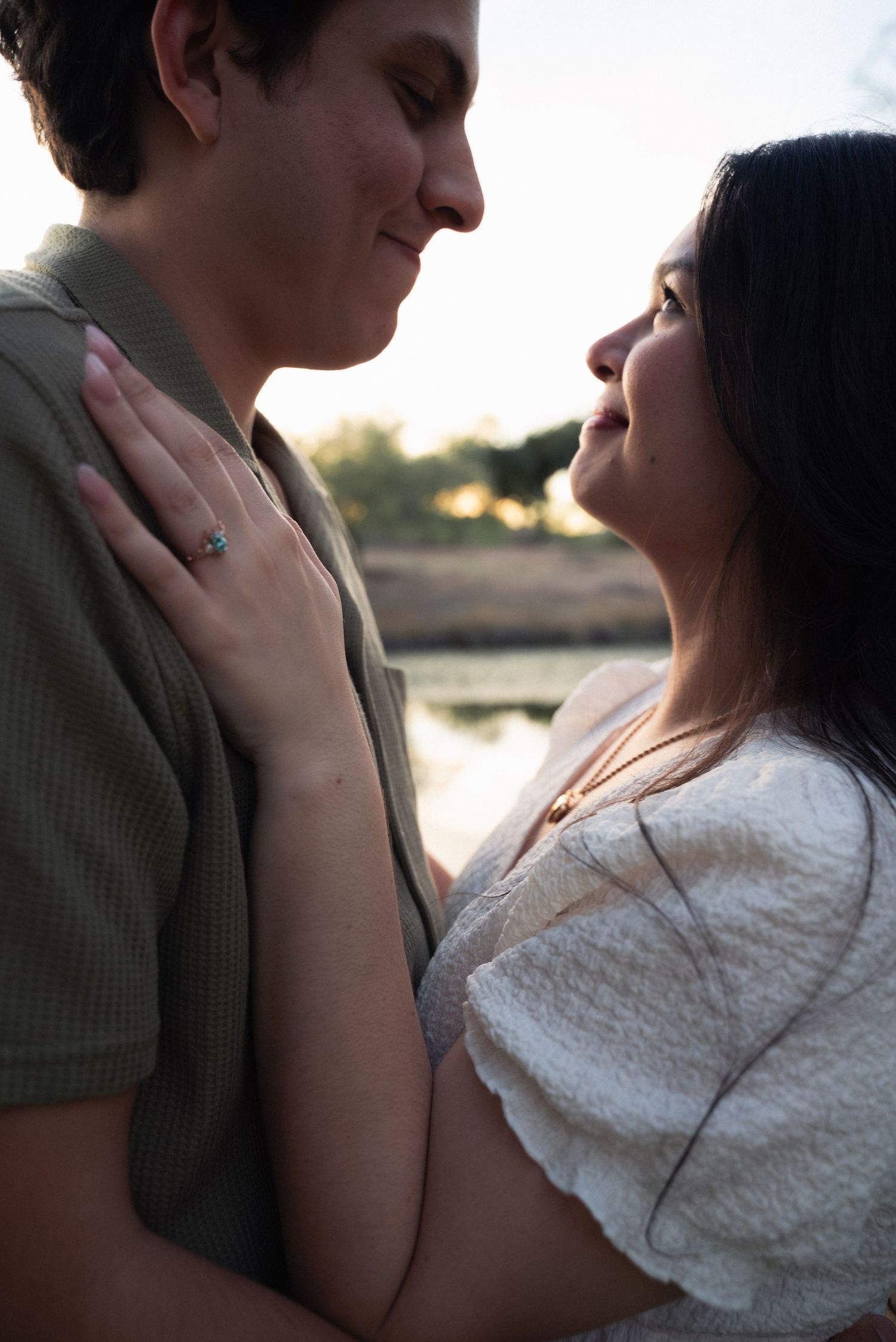 A romantic couple embraces in silhouette against a sunset backdrop near water, creating an intimate moment.