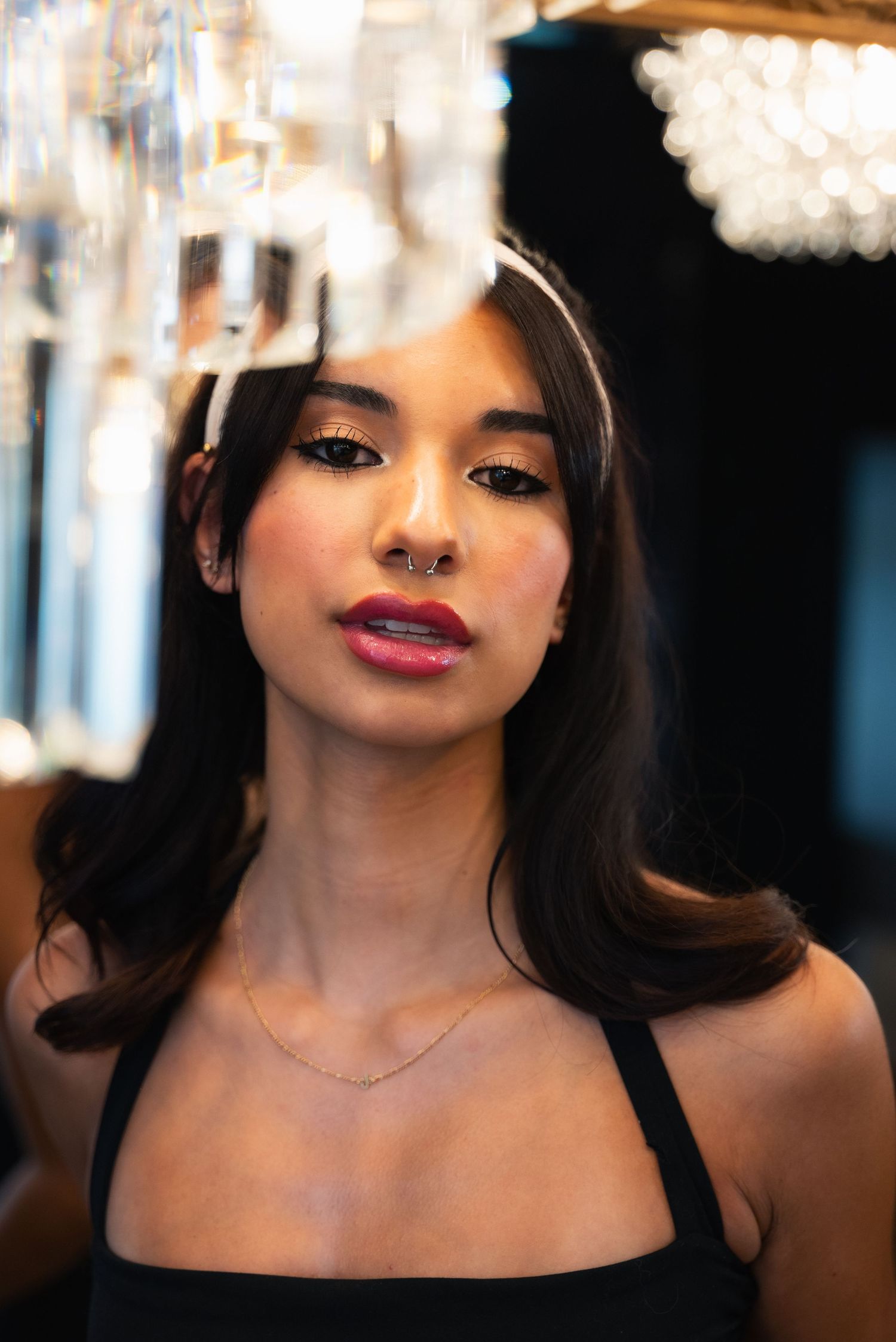 Portrait series showing dramatic makeup with red lipstick and dark eye shadow against a blurred chandelier background.