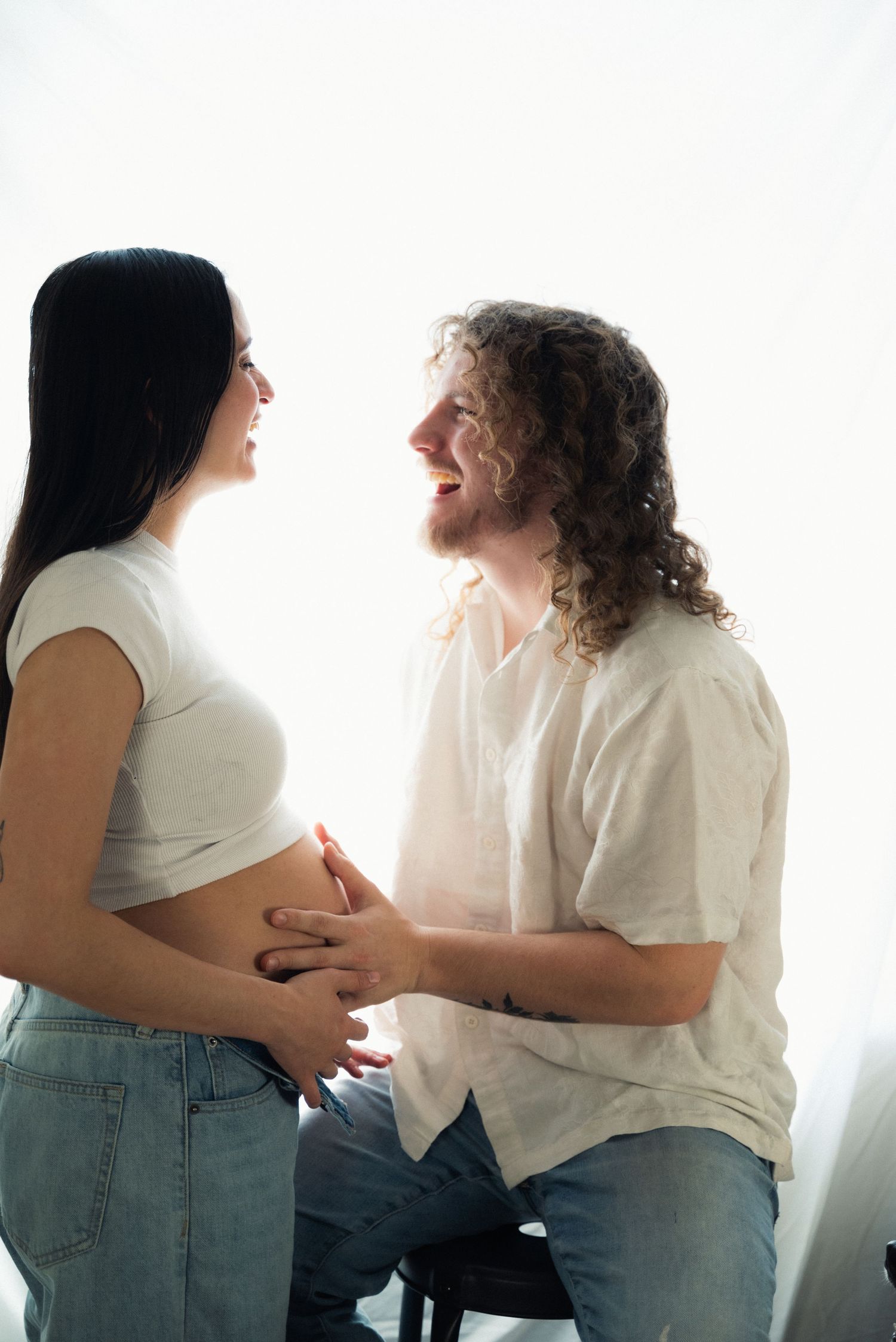Four sequential photos showing a couple in white tops and jeans having an intimate conversation against a bright background.