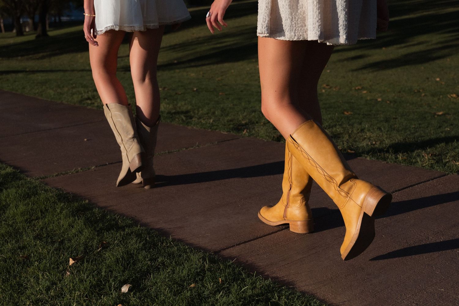 A person wearing yellow rubber rain boots walks along a garden path on a sunny day.