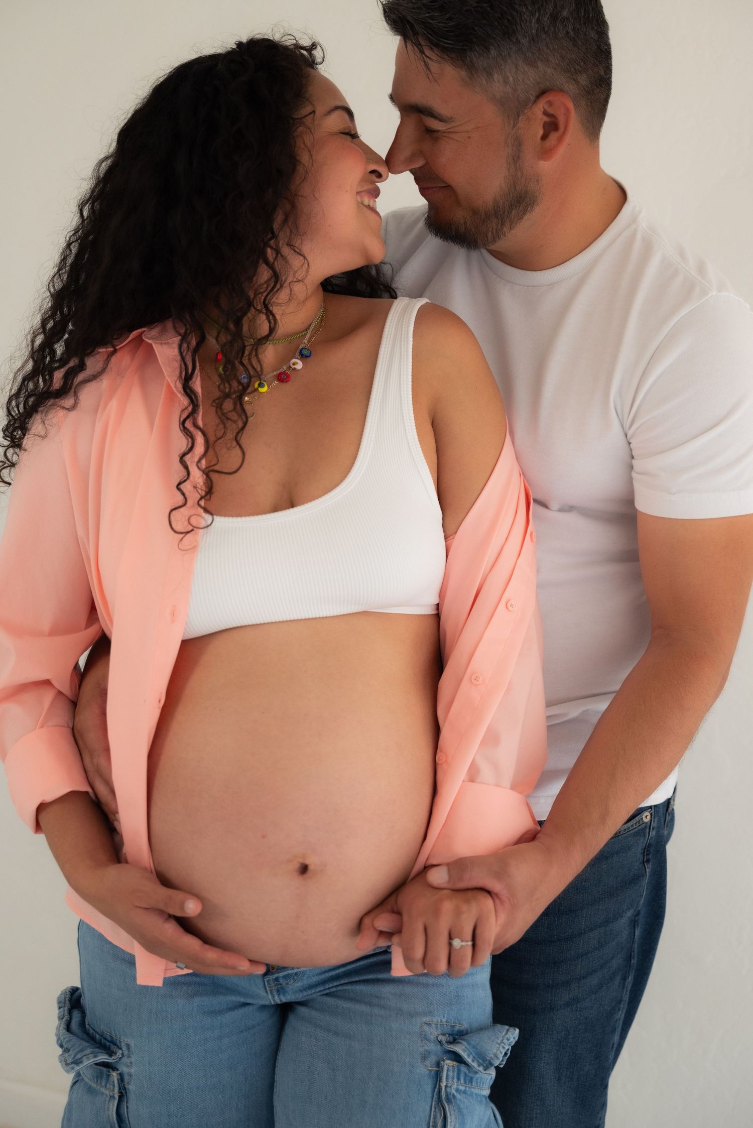 Couple in white shirt and peach blazer sharing intimate moments against white wall in progressive photo series.