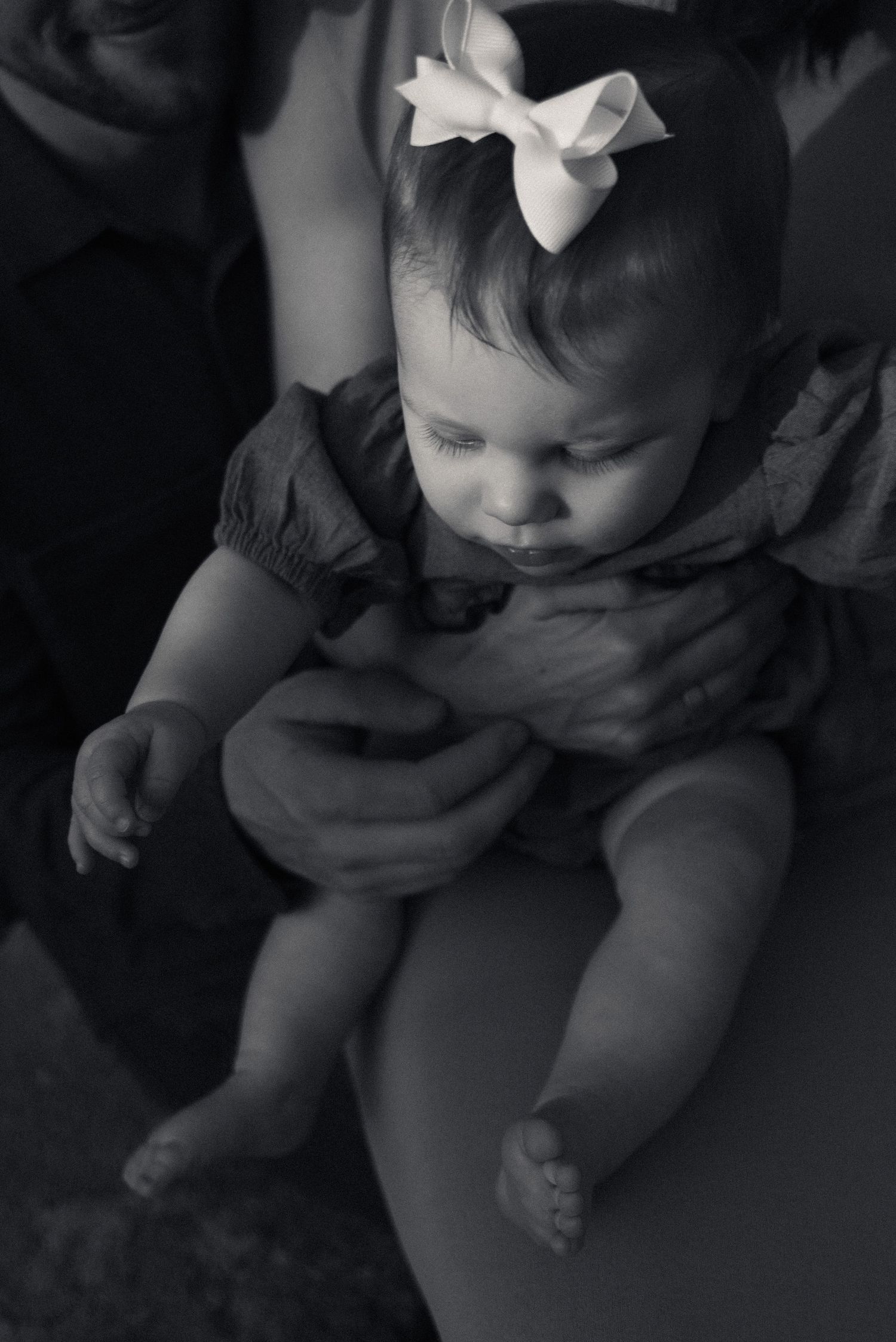 A series of black and white photos showing a baby in different poses wearing a white bow.