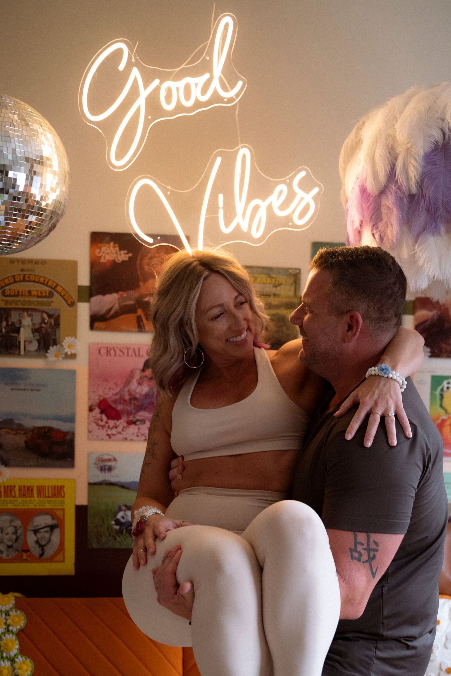 Couple dancing intimately in a vintage-style room with neon signs and retro posters on the wall.