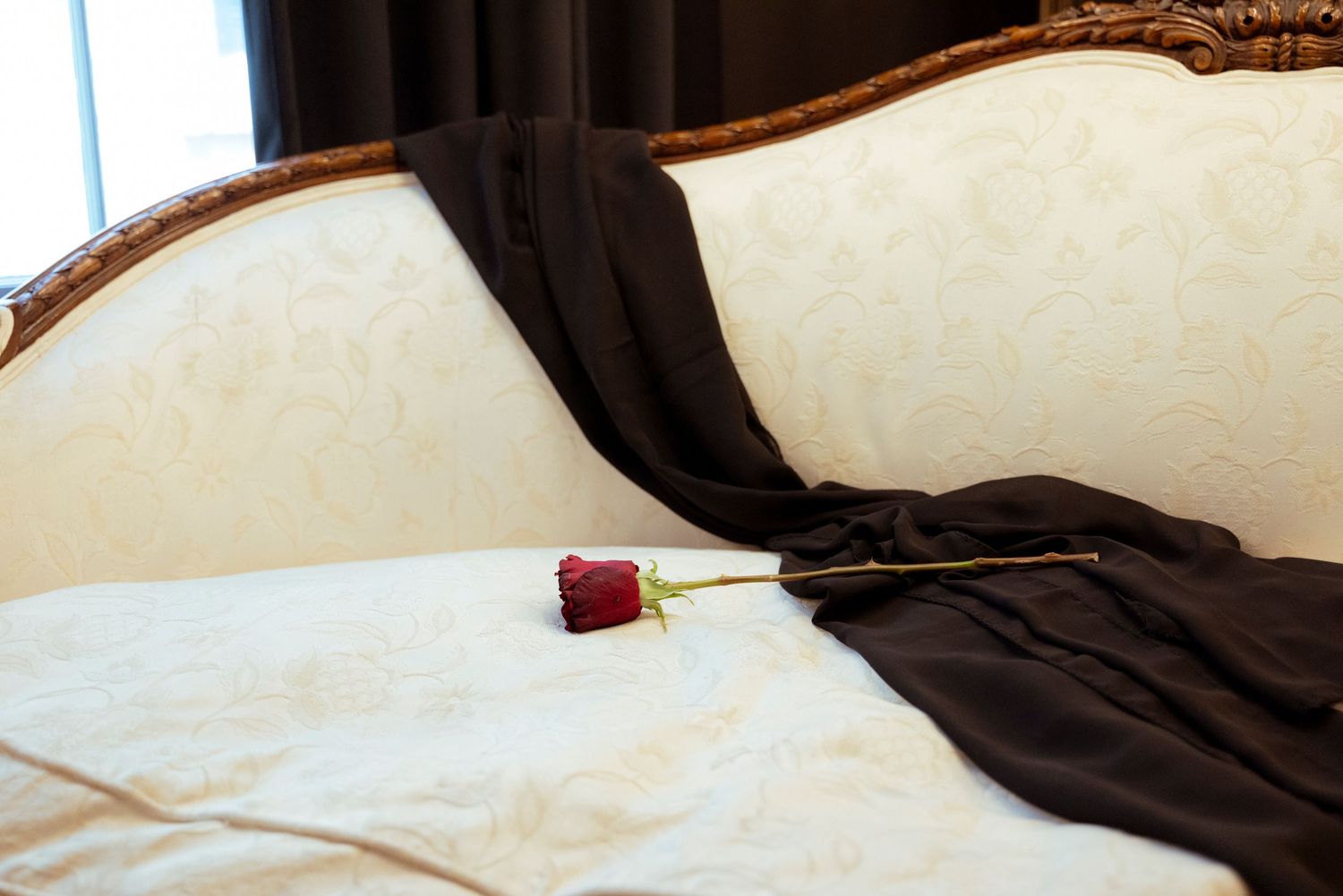 A spacious bedroom with white linens on the bed and brown wooden bed frame with intricate details.