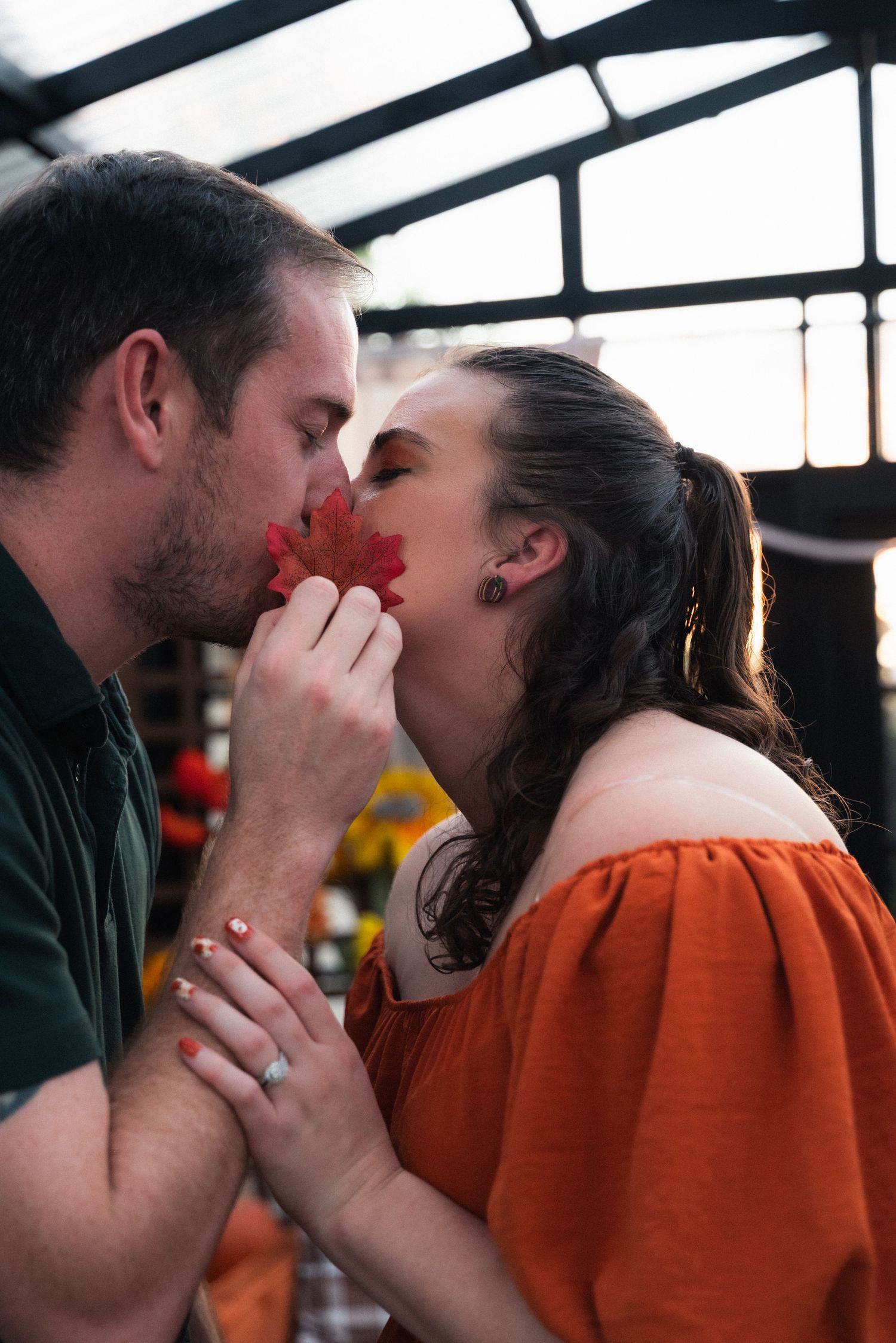 Romantic silhouettes in a greenhouse with autumn decor and natural lighting.