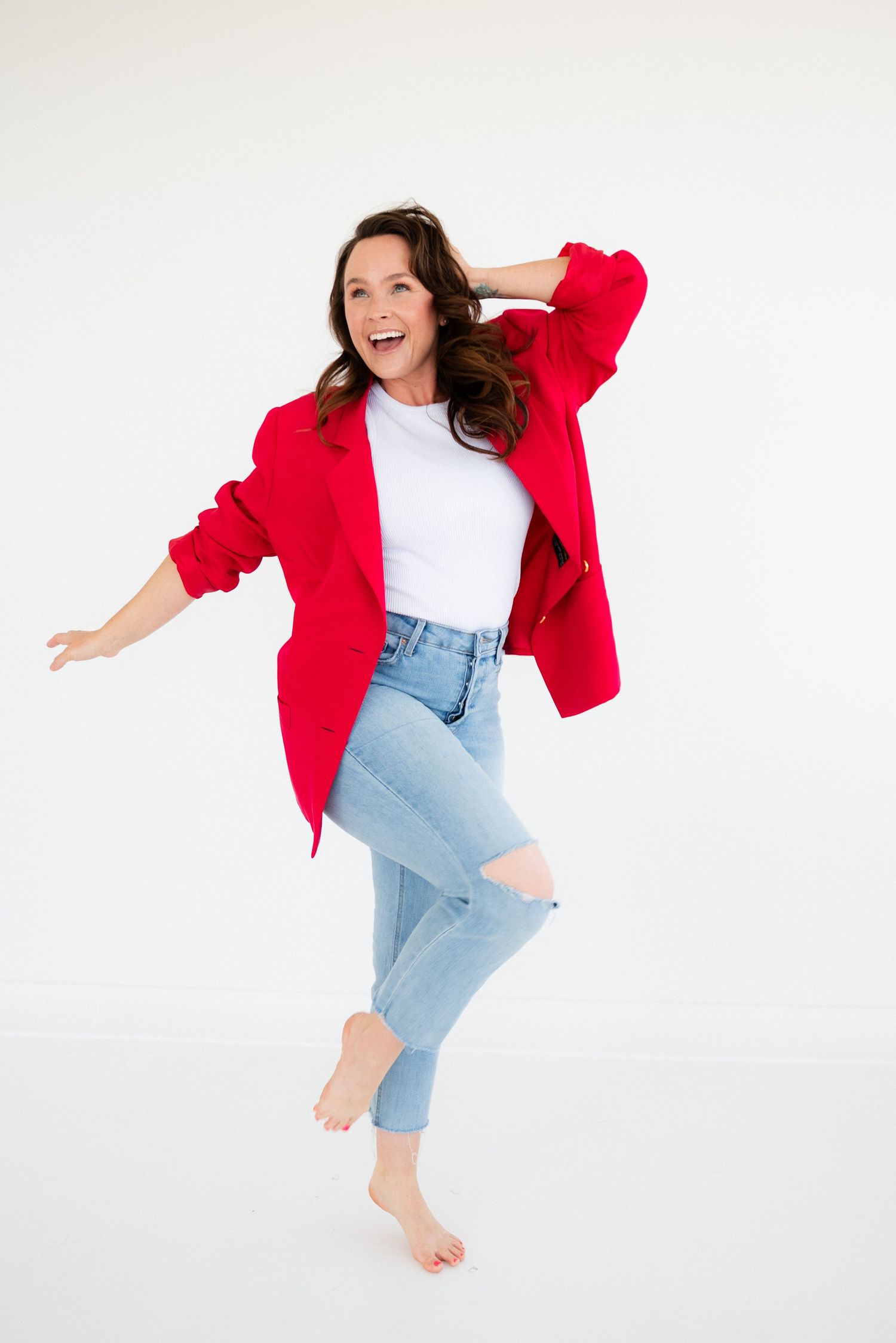 Energetic figure in light denim and red cardigan jumps playfully against white background in dynamic photo sequence.