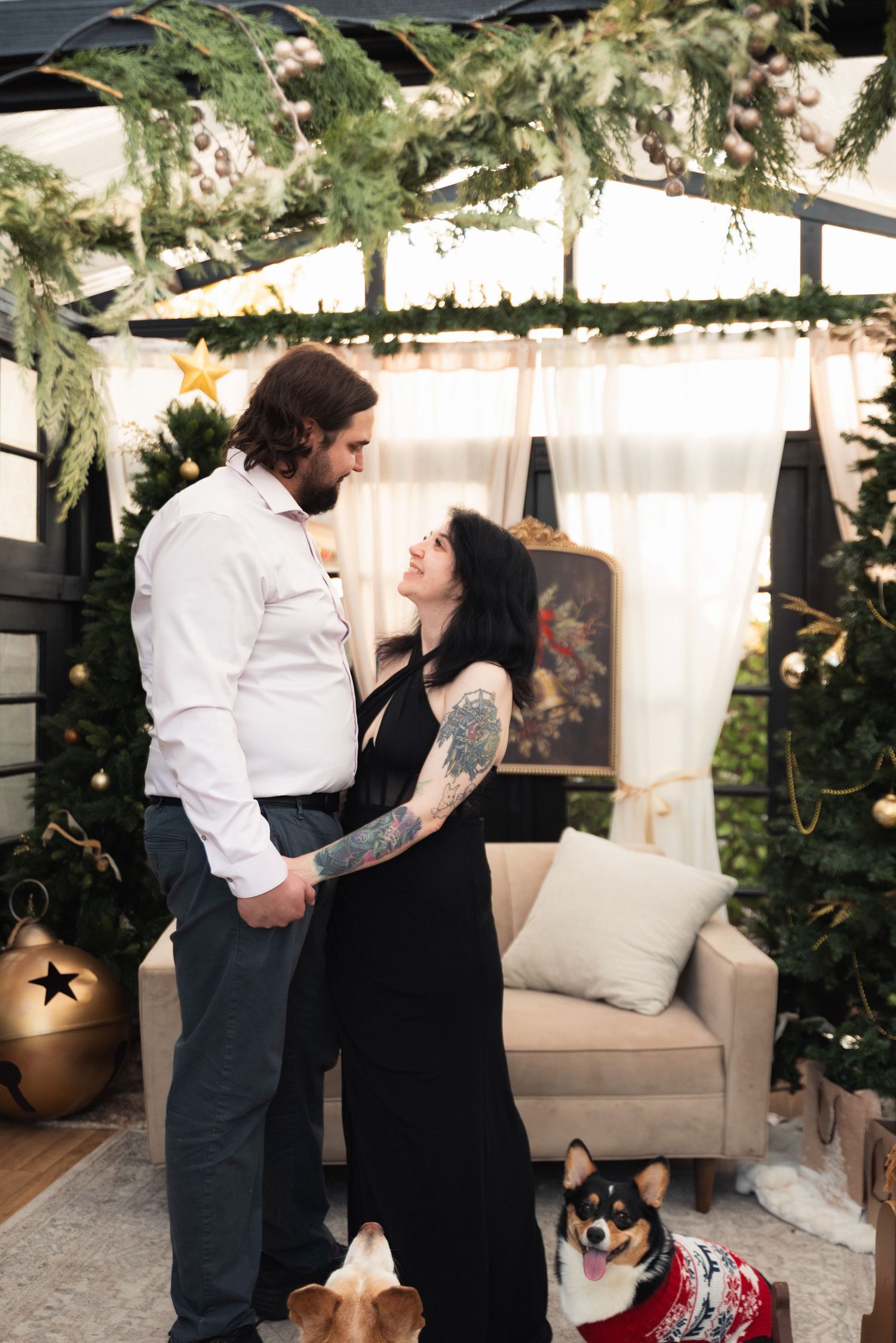 A couple in formal attire shares an intimate moment in a cozy indoor setting with greenery and white decor.