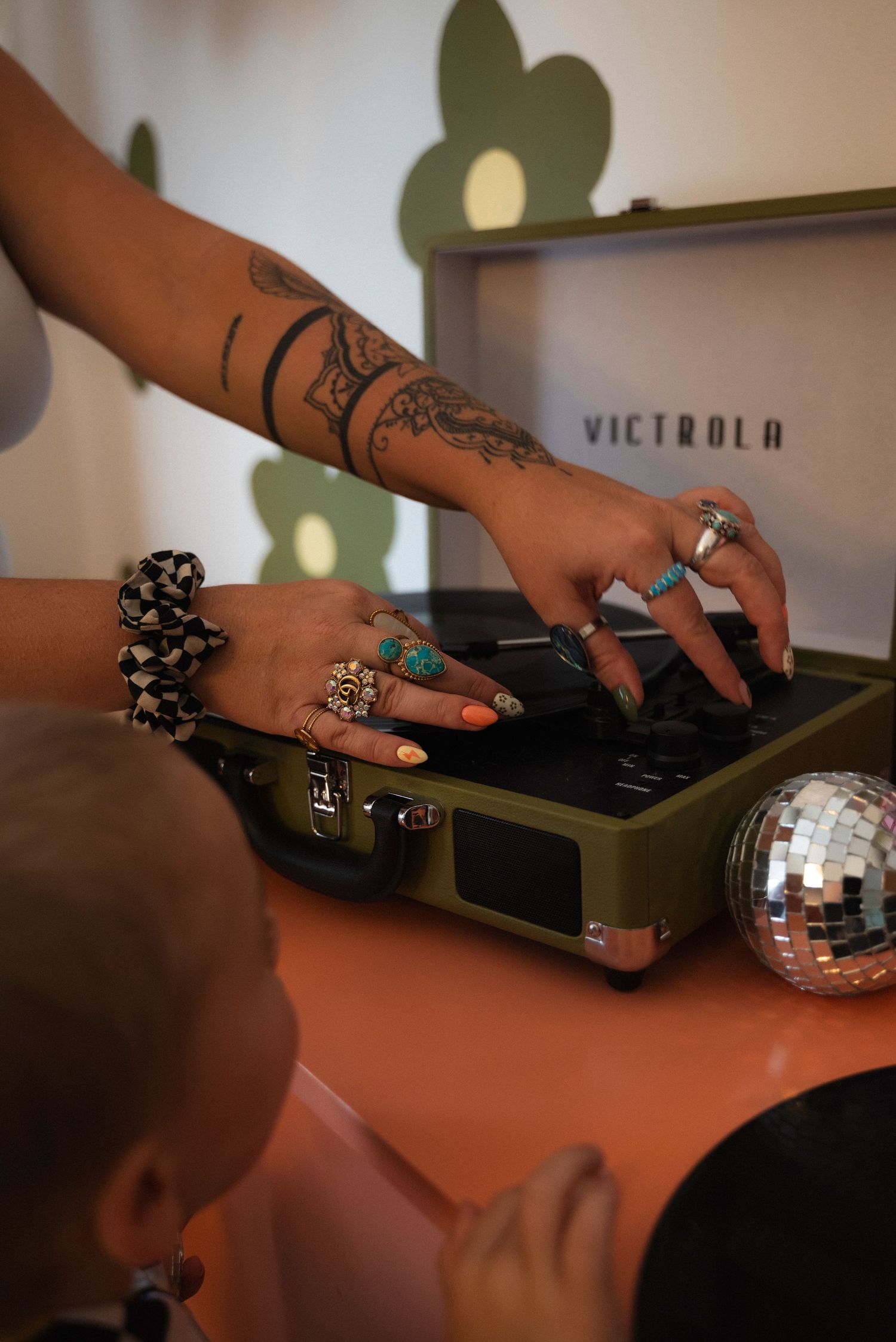 Close-up of hands with rings operating a vintage Victrola record player turntable.