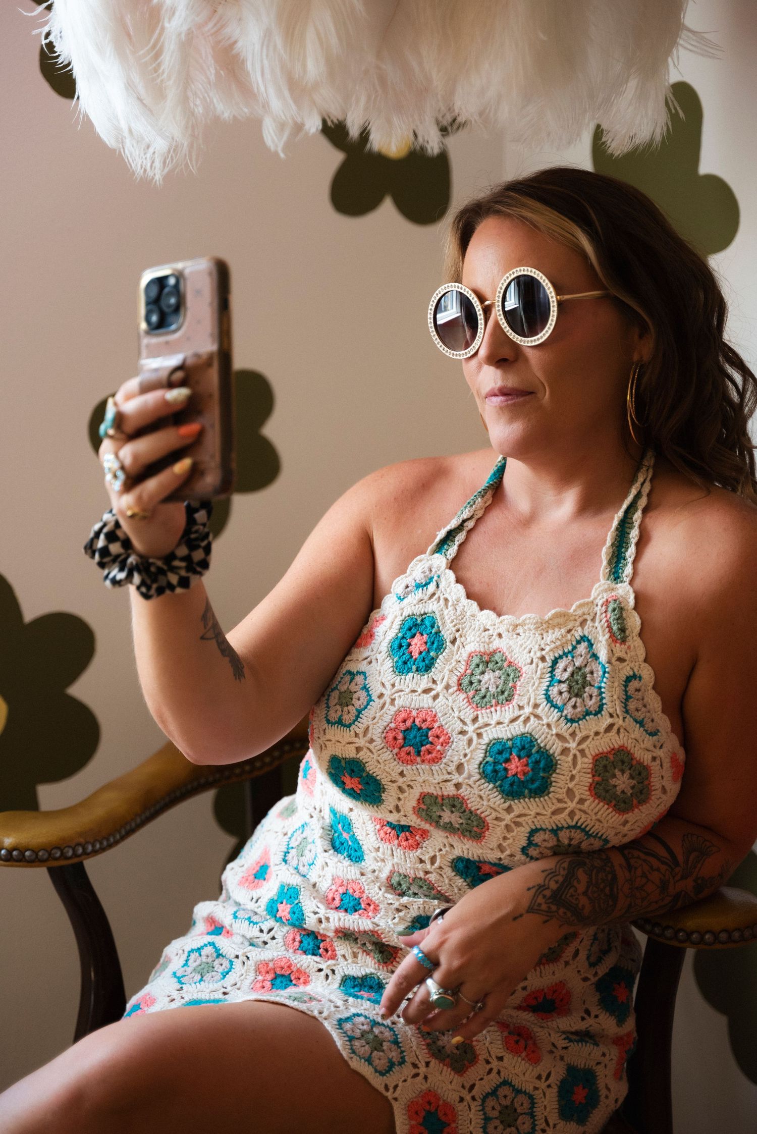 A person in a floral patterned sundress takes selfies in various poses against a neutral wall.