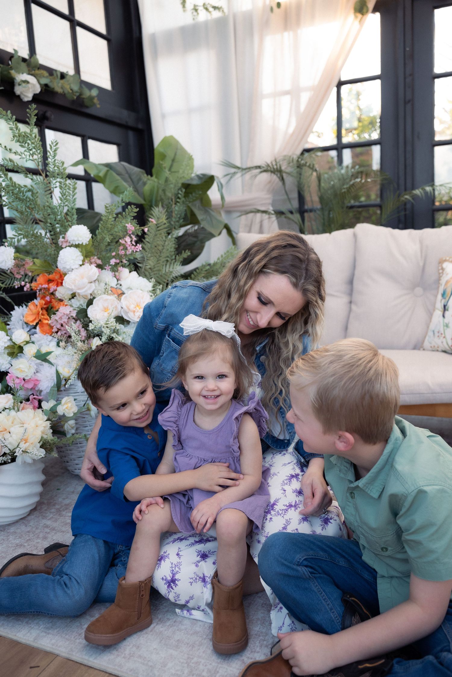 A series of candid family photos showing playful moments on a couch with decorative floral arrangements in the background.