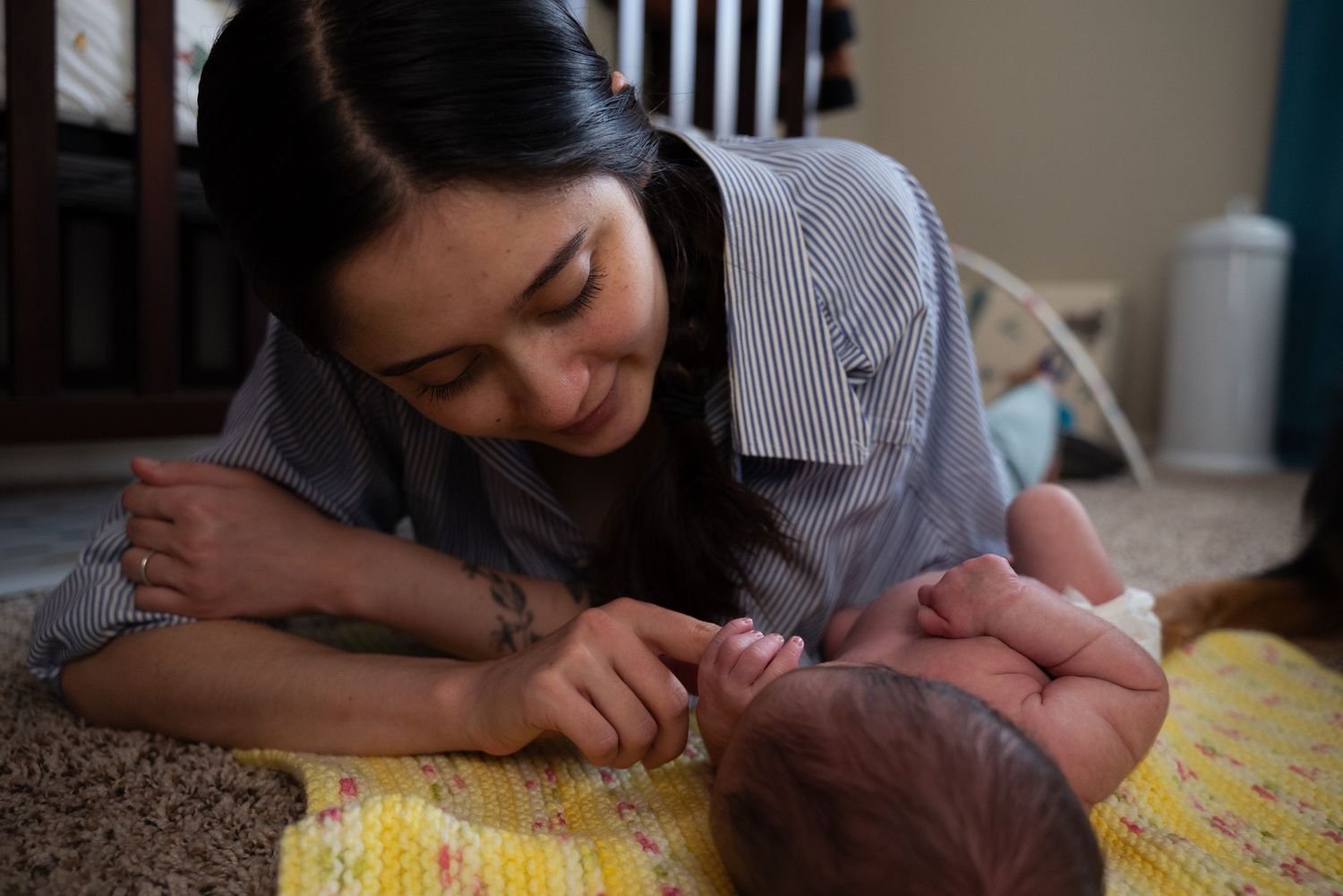 A tender moment of care and bonding with a baby on a yellow patterned blanket.