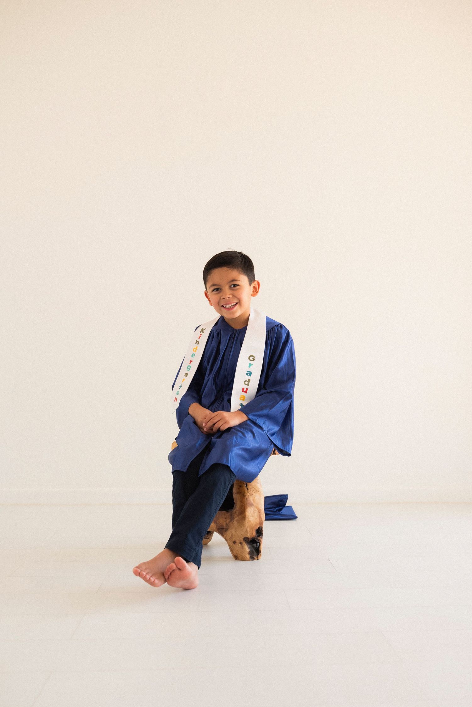 A person in a blue kimono-style robe sits and poses in a series of minimalist photos against a white background.