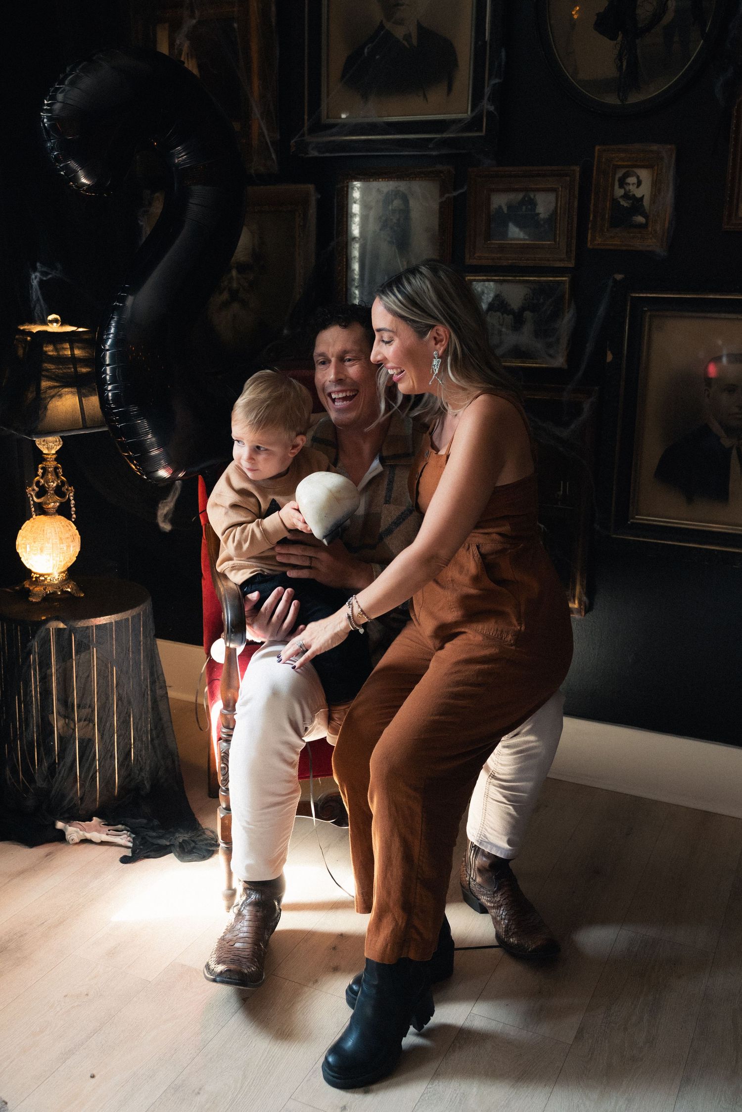 A parent in brown clothing kneels down to comfort a small child in a white shirt in a dimly lit room.