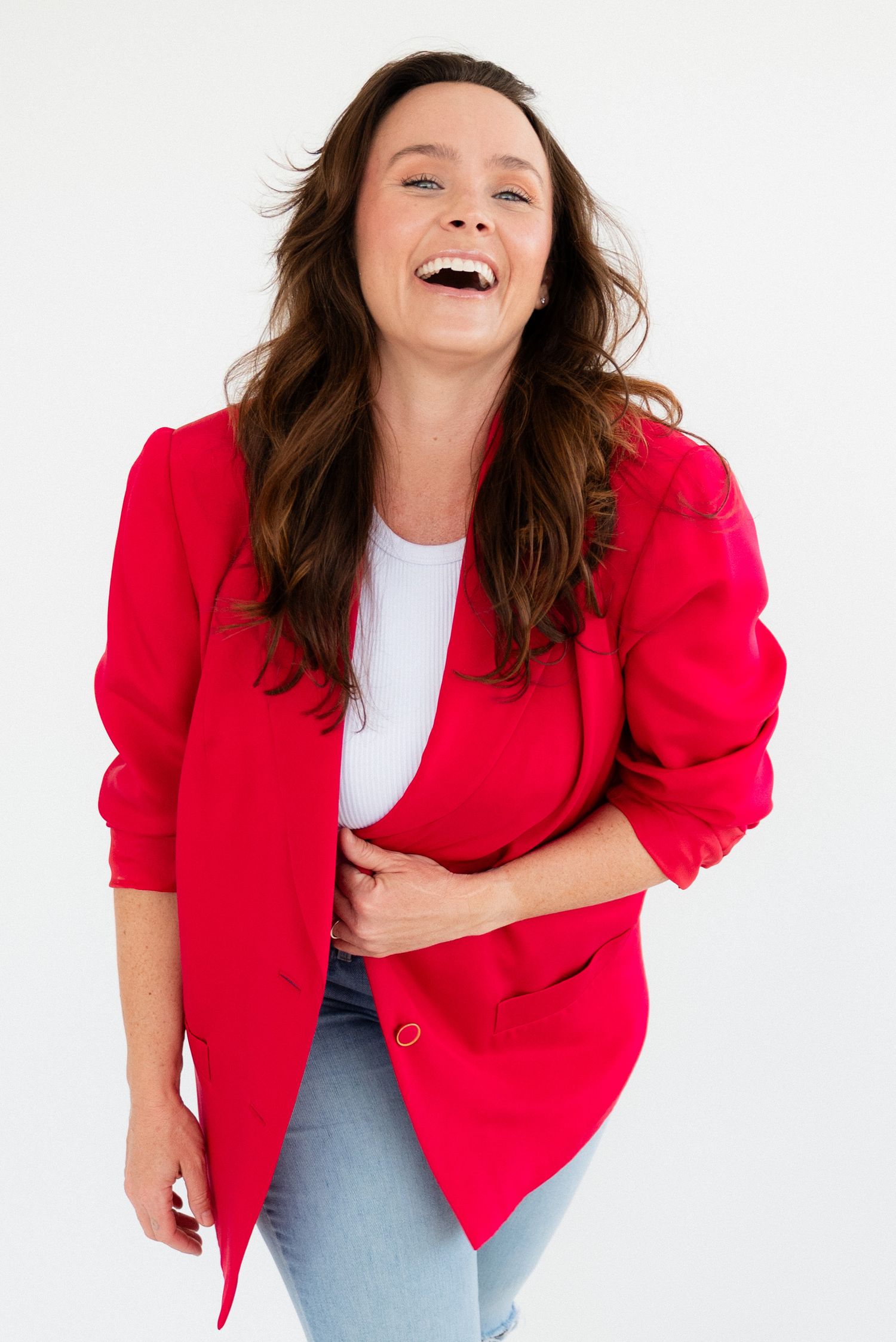 A woman in a red blazer and white shirt laughs joyfully in a series of three expressive studio photos.